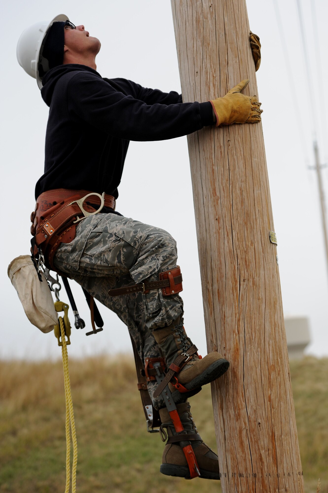 Airman 1st Class Daniel Hatfield, 28th Civil Engineer Squadron electrical systems apprentice, climbs a utility pole during routine maintenance at Ellsworth Air Force Base, S.D., Sept. 9, 2014. Electrical systems Airmen also maintain systems such as the street lights which now run LED lights following a Department of Energy project that reduced the base’s overall energy consumption by 65 percent. (U.S. Air Force photo by Senior Airman Hailey R. Staker/Released)