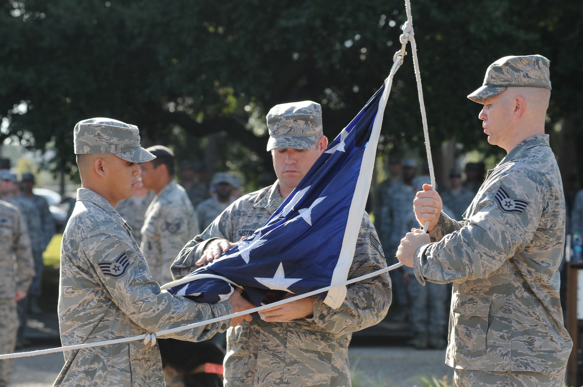 Staff Sgts. Seth Souza, Francis Armstrong and Joshua Williams, 333rd Training Squadron, prepare to raise the flag so that it can then be lowered to half-staff during a remembrance ceremony Sept. 11, 2014, Keesler Air Force Base, Miss. The ceremony honored those who lost their lives during the 9/11 attacks.  (U.S. Air Force photo by Kemberly Groue)