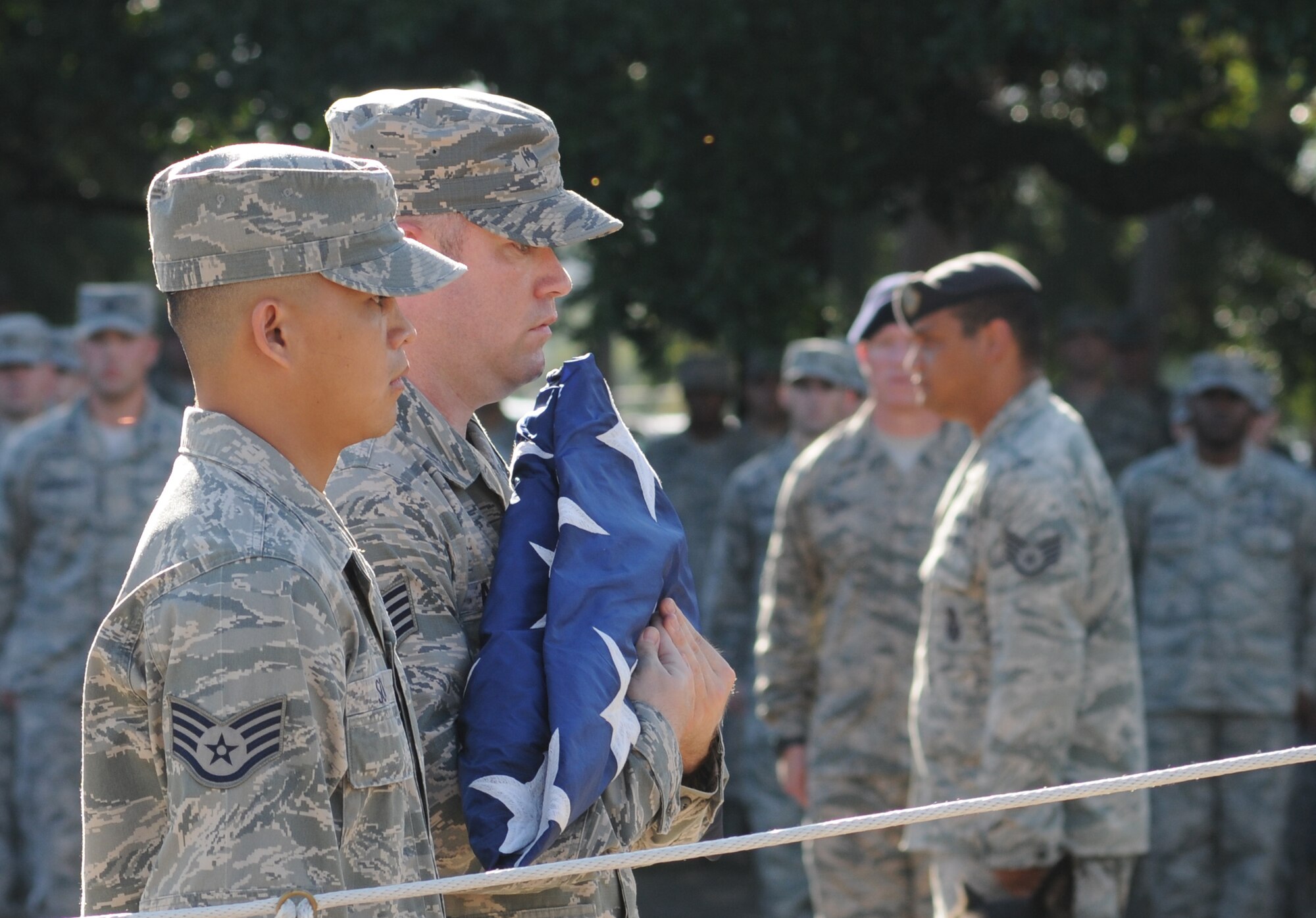 Staff Sgts. Seth Souza and Francis Armstrong, 333rd Training Squadron, prepare to raise the flag so that it can then be lowered to half-staff during a remembrance ceremony Sept. 11, 2014, Keesler Air Force Base, Miss. The ceremony honored those who lost their lives during the 9/11 attacks.  (U.S. Air Force photo by Kemberly Groue)