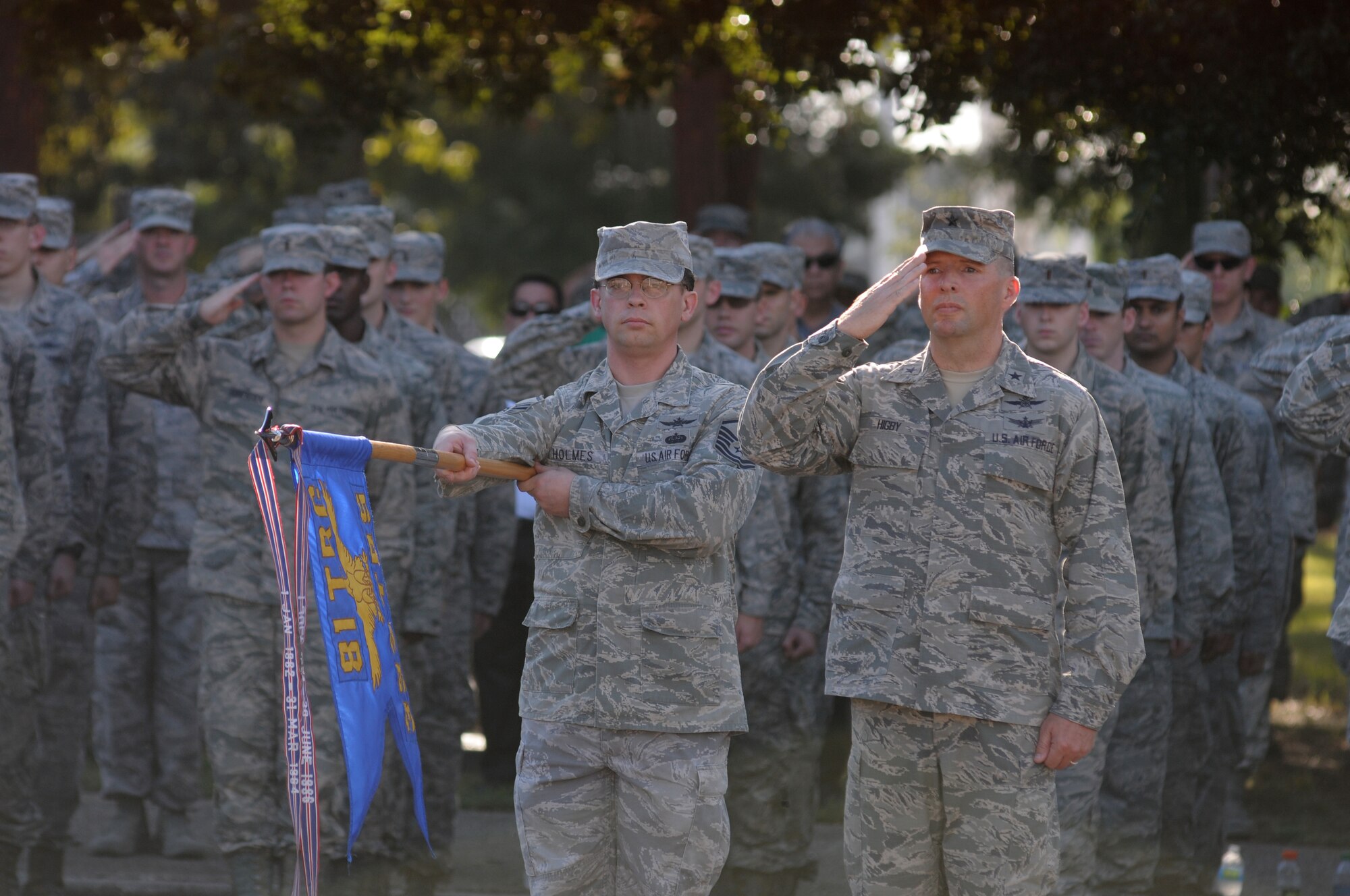Master Sgt. Ezra Holmes, 333rd Training Squadron, holds the 333rd TRS flag while Brig. Gen. Patrick Higby, 81st Training Wing commander and Keesler personnel render a salute as the flag is lowered to half-staff during a remembrance ceremony Sept. 11, 2014, Keesler Air Force Base, Miss. The ceremony honored those who lost their lives during the 9/11 attacks.  (U.S. Air Force photo by Kemberly Groue)