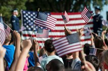 Children wave flags in reaction to the flag-folding ceremony performed by the Travis Air Force Base Honor Guard during the America Supports You Freedom Walk Ceremony Sept.11, 2014, at Travis. Schoolchildren from Travis School District schools attended the walk, a national tradition that calls on people to reflect on the lives lost on 9/11, remember those who responded, honor our veterans past and present and renew the commitment to freedom and the values of the country. (U.S. Air Force photo by Heide Couch)