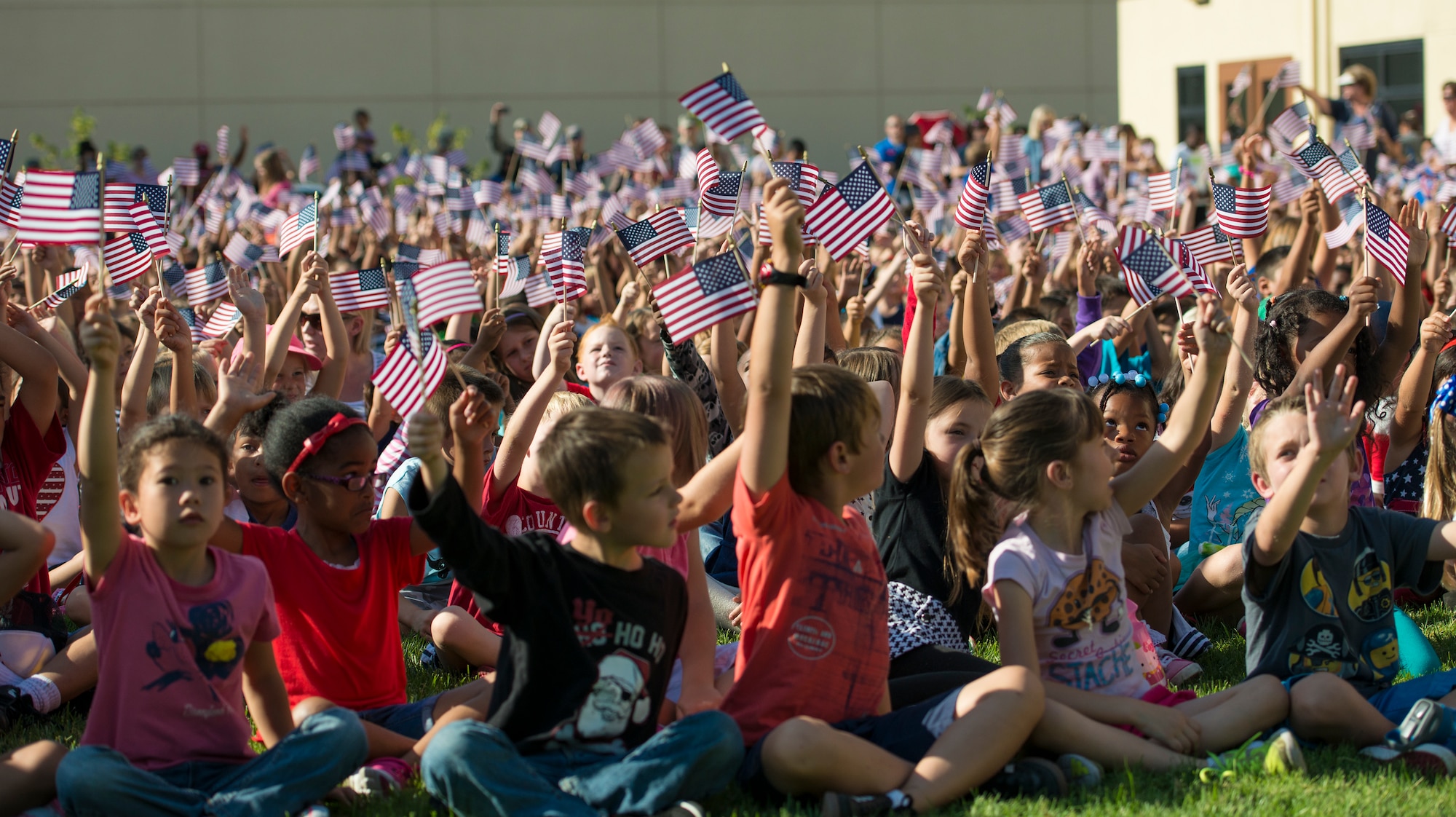 Children wave flags in reaction to the flag-folding ceremony performed by the Travis Air Force Base Honor Guard during the America Supports You Freedom Walk Ceremony Sept.11, 2014, at Travis. Schoolchildren from Travis School District schools attended the walk, a national tradition that calls on people to reflect on the lives lost on 9/11, remember those who responded, honor our veterans past and present and renew the commitment to freedom and the values of the country. (U.S. Air Force photo by Heide Couch)