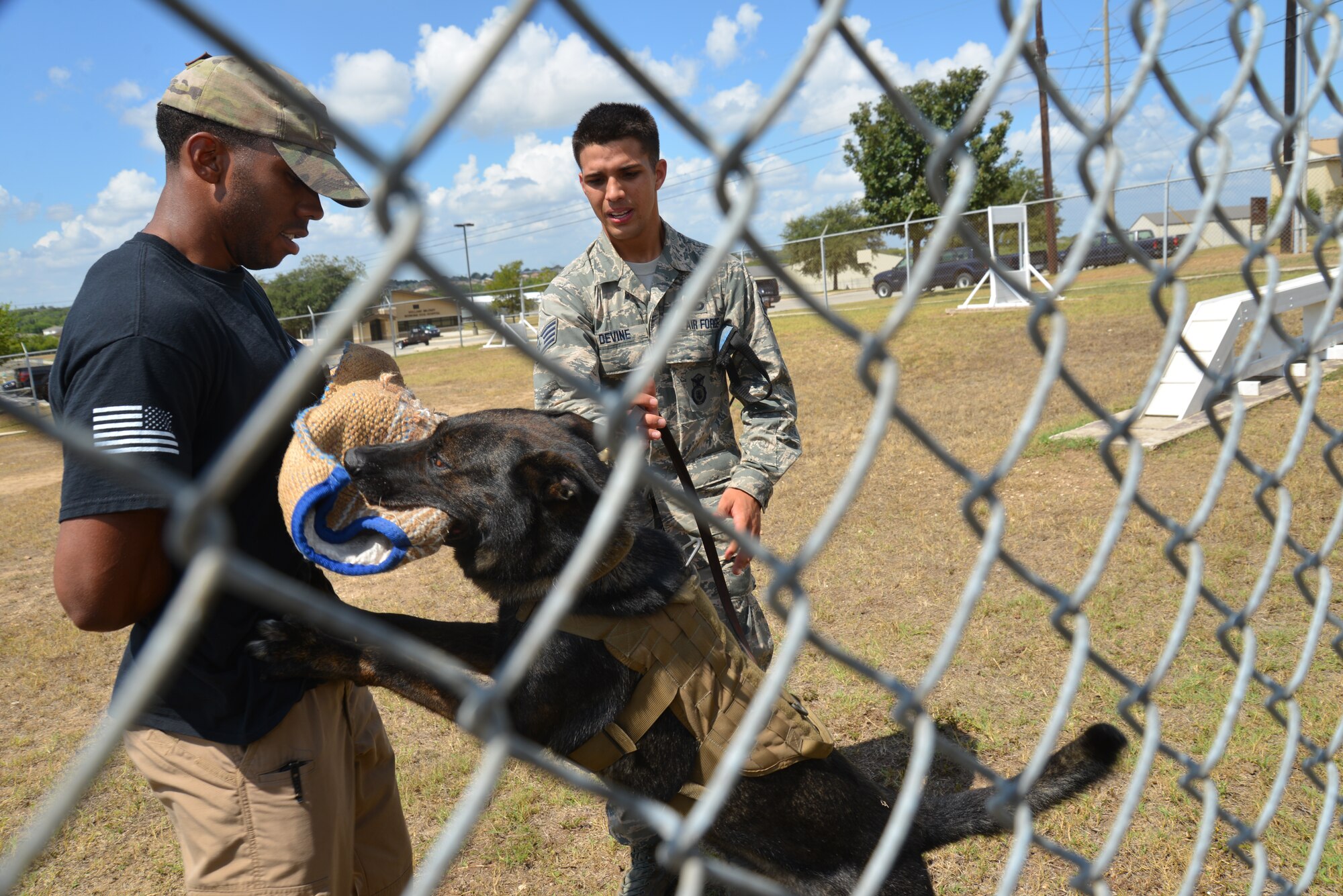 Staff Sgt. Sharif DeLarge (left) and Staff Sgt. Mark Devine, both dog handlers and Jany, an MWD from the 802nd Security Forces Military Working Dog Squadron, Joint Base San Antonio-Lackland, Texas demonstrate different basic attack maneuvers during an 433rd Mission Support Group Honorary Commanders' tour, Sept. 6, 2014. (U.S. Air Force photo/Minnie Jones)  