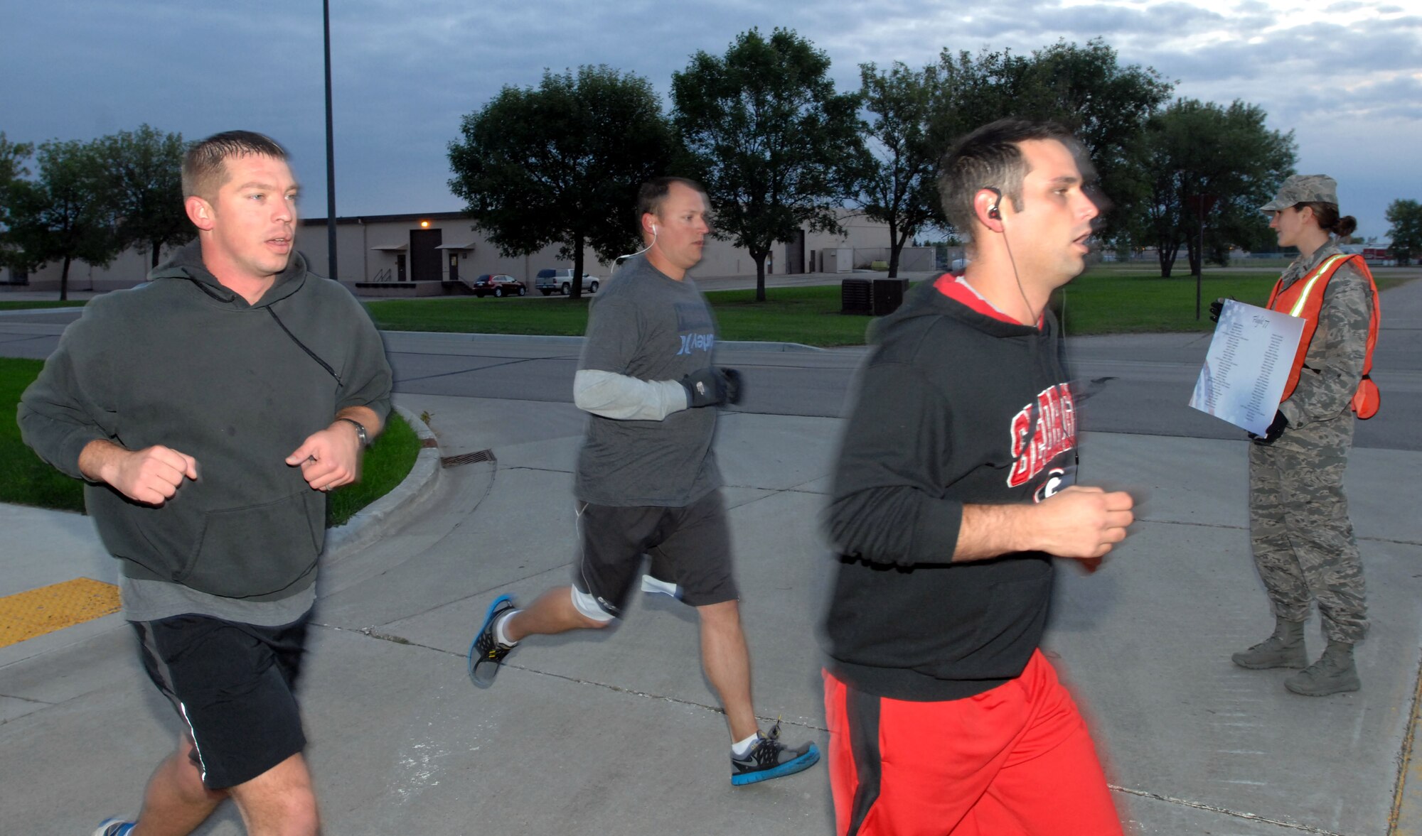 Second Lt. Suzann Watson, 319th Force Support Squadron, holds up a sign listing the names of victims of the Sept. 11, 2001, terrorist attacks as runners pass by, Sept. 11, 2014 on Grand Forks Air Force Base, N.D. The runners participated in a 5k and a 9.11k run to honor the memory of the victims of the attacks. (U.S. Air Force photo/Staff Sgt. Susan L. Davis)