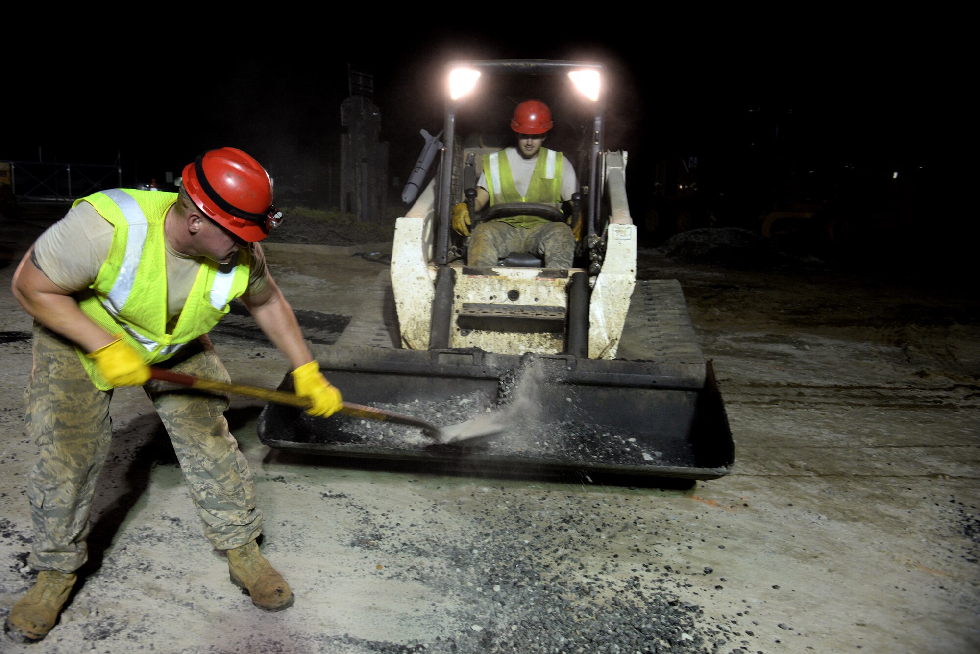 U.S. Air Force Senior Airman John Carroll (left), and Staff Sgt. John Farmer, both 823rd Rapid Engineer Deployable Heavy Operational Repair Squadron Engineers pavements and equipment operator journeyman, assigned to Hurlburt  Field, Fla., work together to move asphalt during a construction project at Shaw Air Force Base, S.C., Sept. 10, 2014. Road pavements are done at night to keep the asphalt at a regulated temperature. Hot asphalt is initially raked by the crew to spread it out before it is rolled over by a steel-wheel roller. (U.S. Air Force photo by Airman 1st Class Jonathan Bass/Released)
