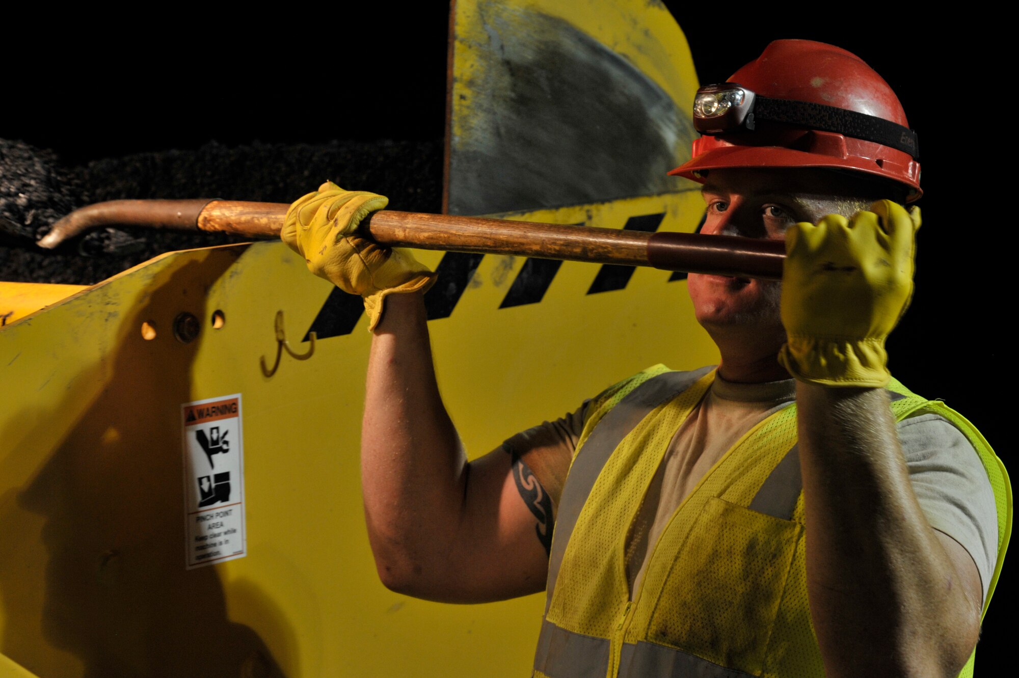 U.S. Air Force Senior Airman John Carroll, 823rd Rapid Engineer Deployable Heavy Operational Repair Squadron Engineers pavements and equipment operator journeyman, assigned to Hurlburt Field, Fla., shovels asphalt from a material transfer vehicle at Shaw Air Force Base, S.C., Sept. 10, 2014. Asphalt is kept at approximately 280 degrees Fahrenheit in order to maintain its malleability. The ‘tar’ smell that occurs during paving is caused by oils being released from within the hot asphalt as it gets smoothed on the road. (U.S. Air Force photo by Airman 1st Class Jonathan Bass/Released)