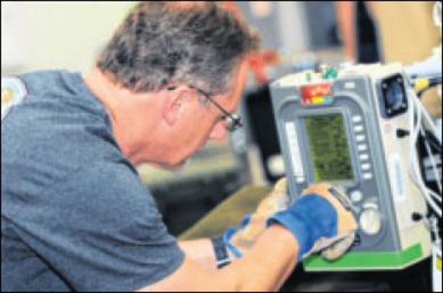 Darryl Walker, Utah 1 Disaster Medical Assistance Team respiratory therapist, programs a respirator for a simulated patient during a joint exercise b etween the Department of Defense and various teams with the National Disaster medical System and its Mobile Acute Care Strike Team. (Air Force photo by Wesley Farnsworth)