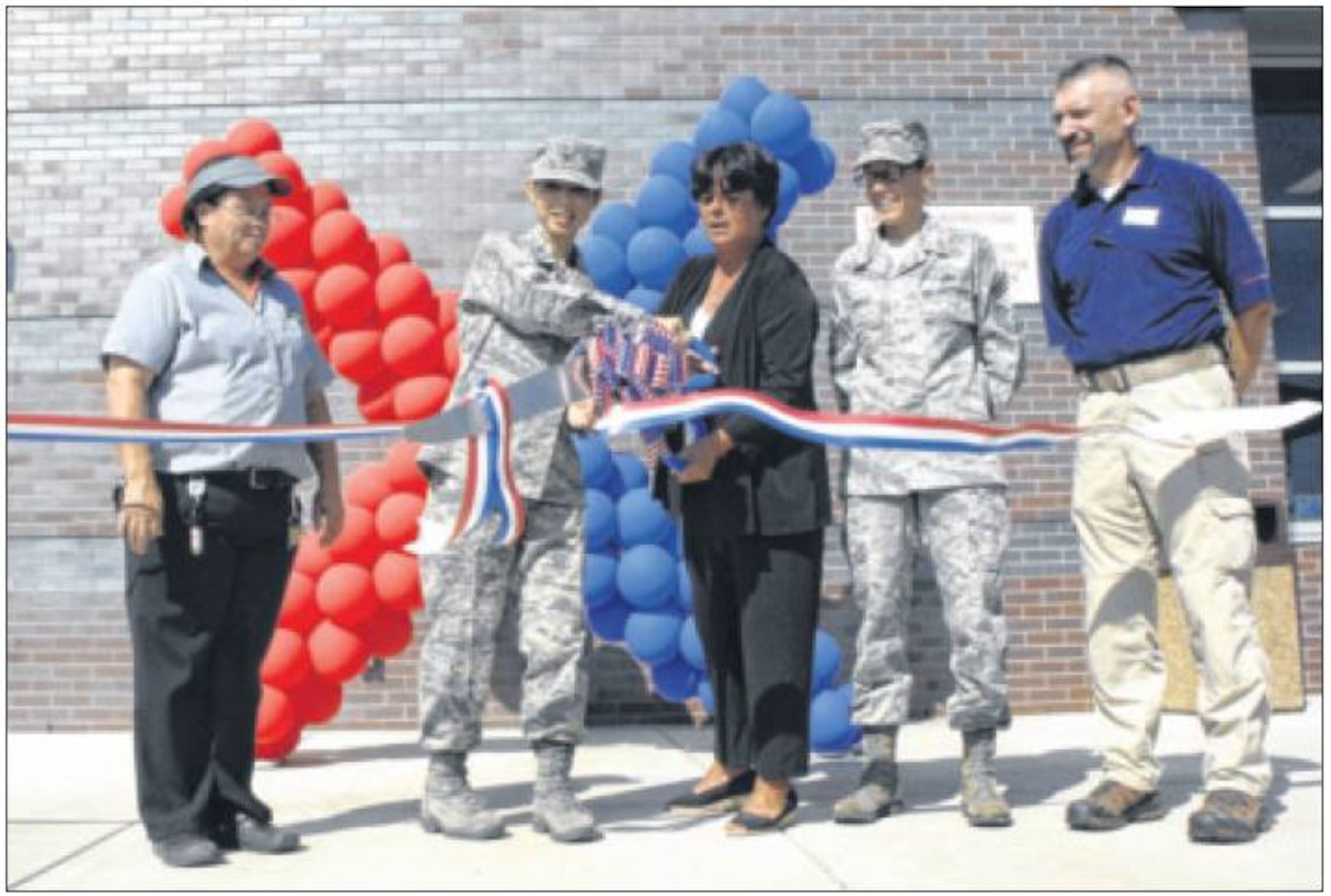 Col. Emi Izawa, 88th Mission Support Group commander (second from left), and Robin Ayling (center) cut the ribbon Sept. 9 in front of the combination Express gas station, shopette and Burger King in Area B. (Air Force photo by Al Bright)