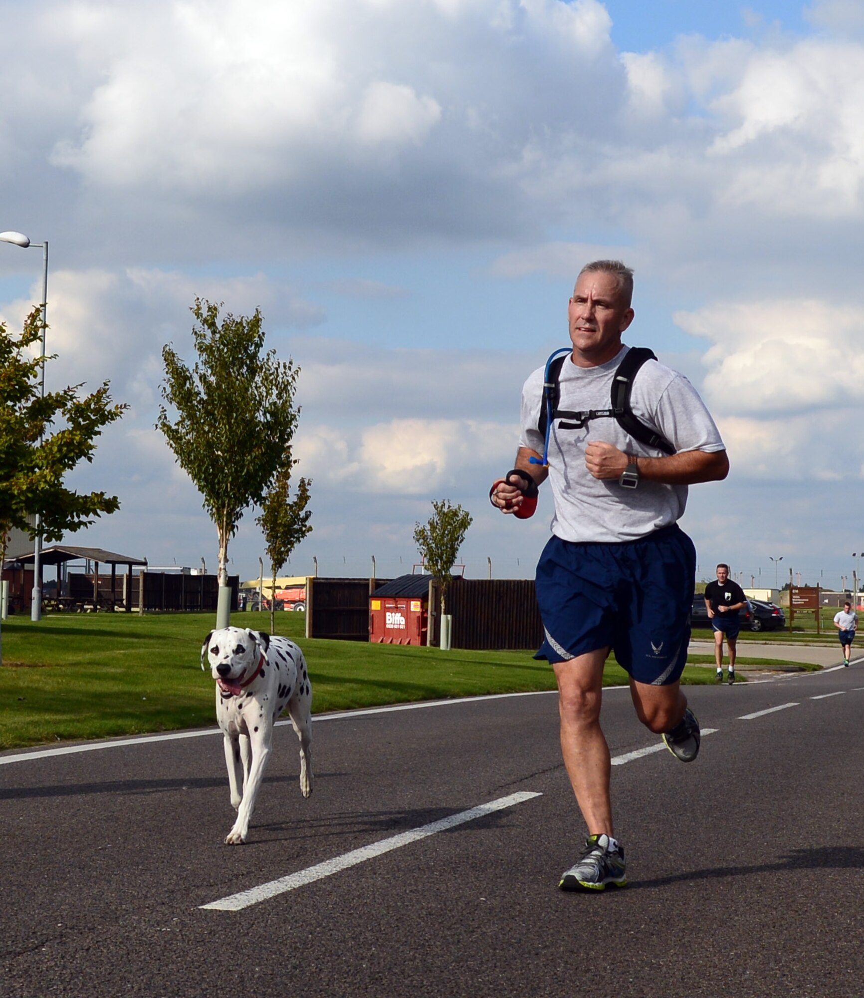 U.S. Air Force Chief Master Sgt. Christopher Mohr, 100th Civil Engineer Squadron fire chief from El Toro, Calif., finishes the last leg of the 100th Air Refueling Wing 5 km run with his dog, Ka, in honor of Prisoner of War/Missing in Action Week of Remembrance Sept. 12, 2014, on RAF Mildenhall, England. Every month, Team Mildenhall members gather for exercise and friendly competition. (U.S. Air Force photo/Airman 1st Class Jonathan Light/Released)
