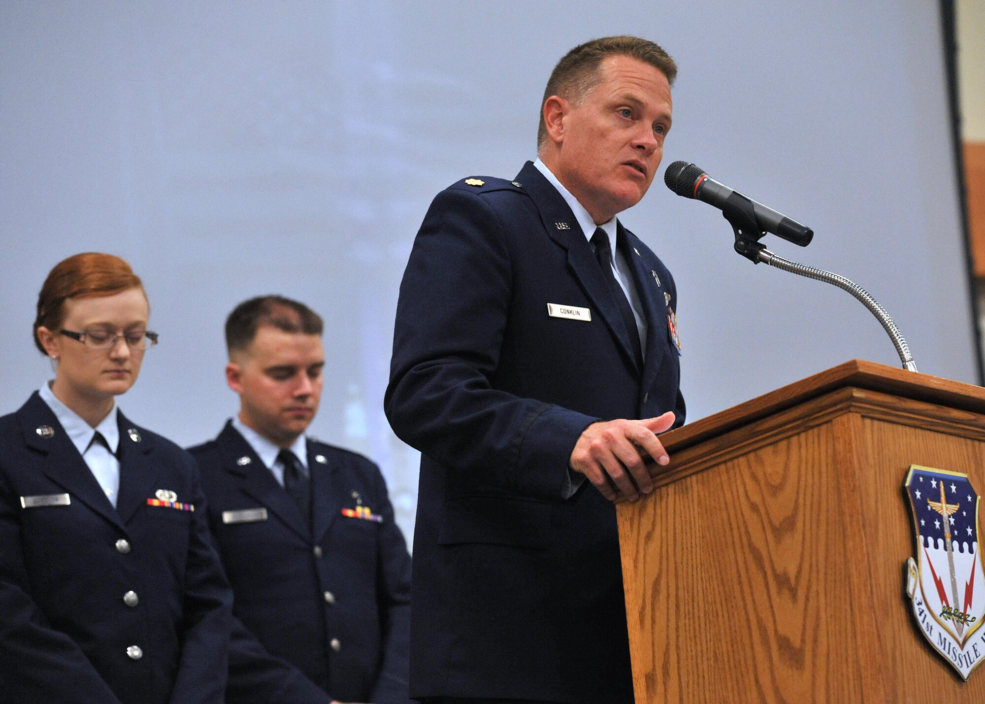 Chaplain (Maj.) Chris Conklin, 341st Missile Wing chaplain, delivers the invocation for the “In Remembrance of 9-11” memorial ceremony Sept. 11 while Airman 1st Class Courtney Gardner, 341st Force Support Squadron chef, and Chaplain (1st Lt.) John Reutemann, 341st MW chaplain, bow their heads. The event was held at the Grizzly Bend. (U.S. Air Force photo/John Turner)