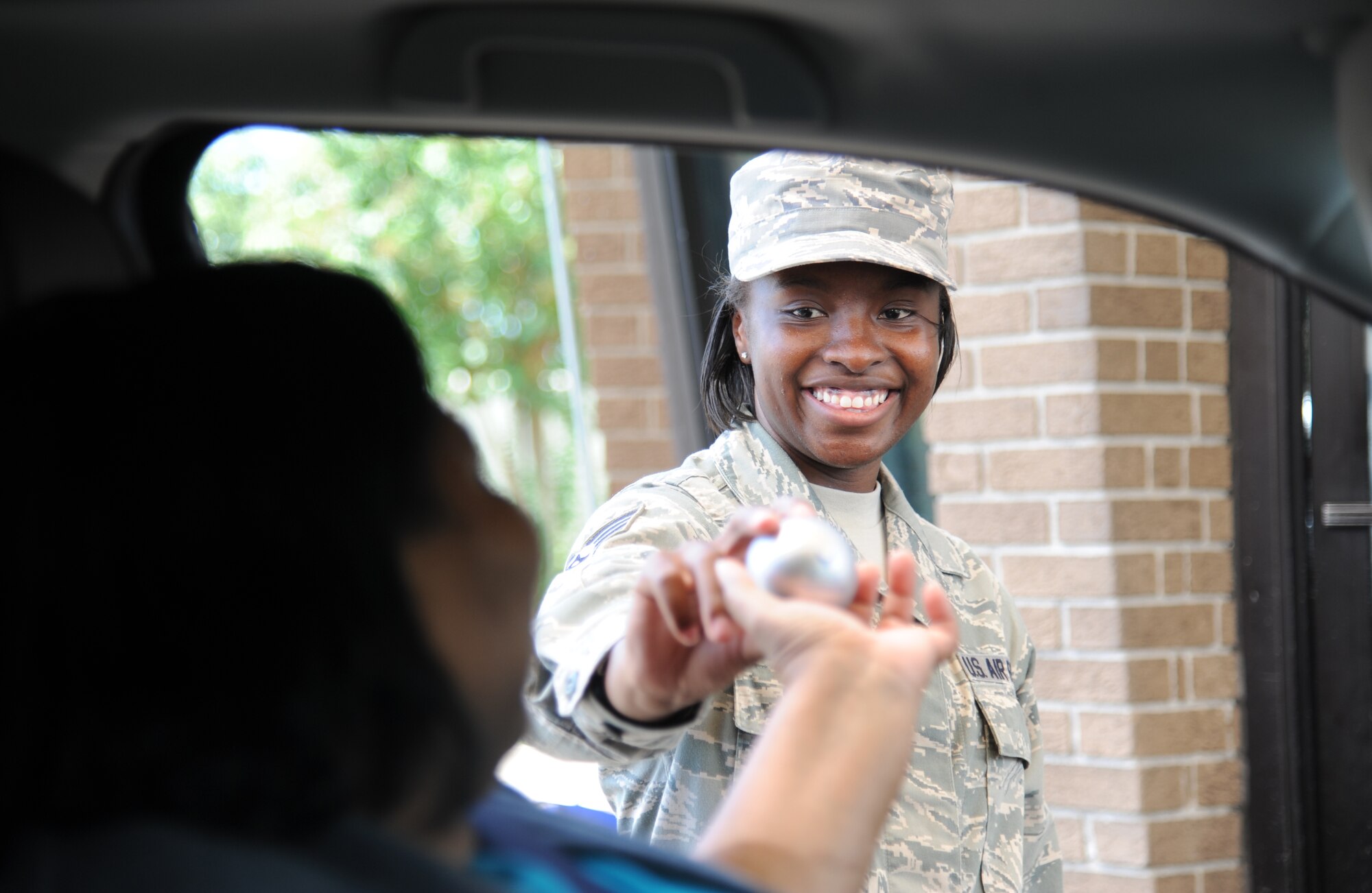 Staff Sgt. Tiffany Andrews, 81st Medical Operations Squadron, hands a suicide prevention awareness stress ball to Cynthia Lee, 81st Contracting Squadron, and other Keesler personnel as they enter the base Sept. 10, 2014, at Keesler Air Force Base, Miss. This task was in recognition of suicide prevention awareness.  (U.S. Air Force photo by Kemberly Groue)