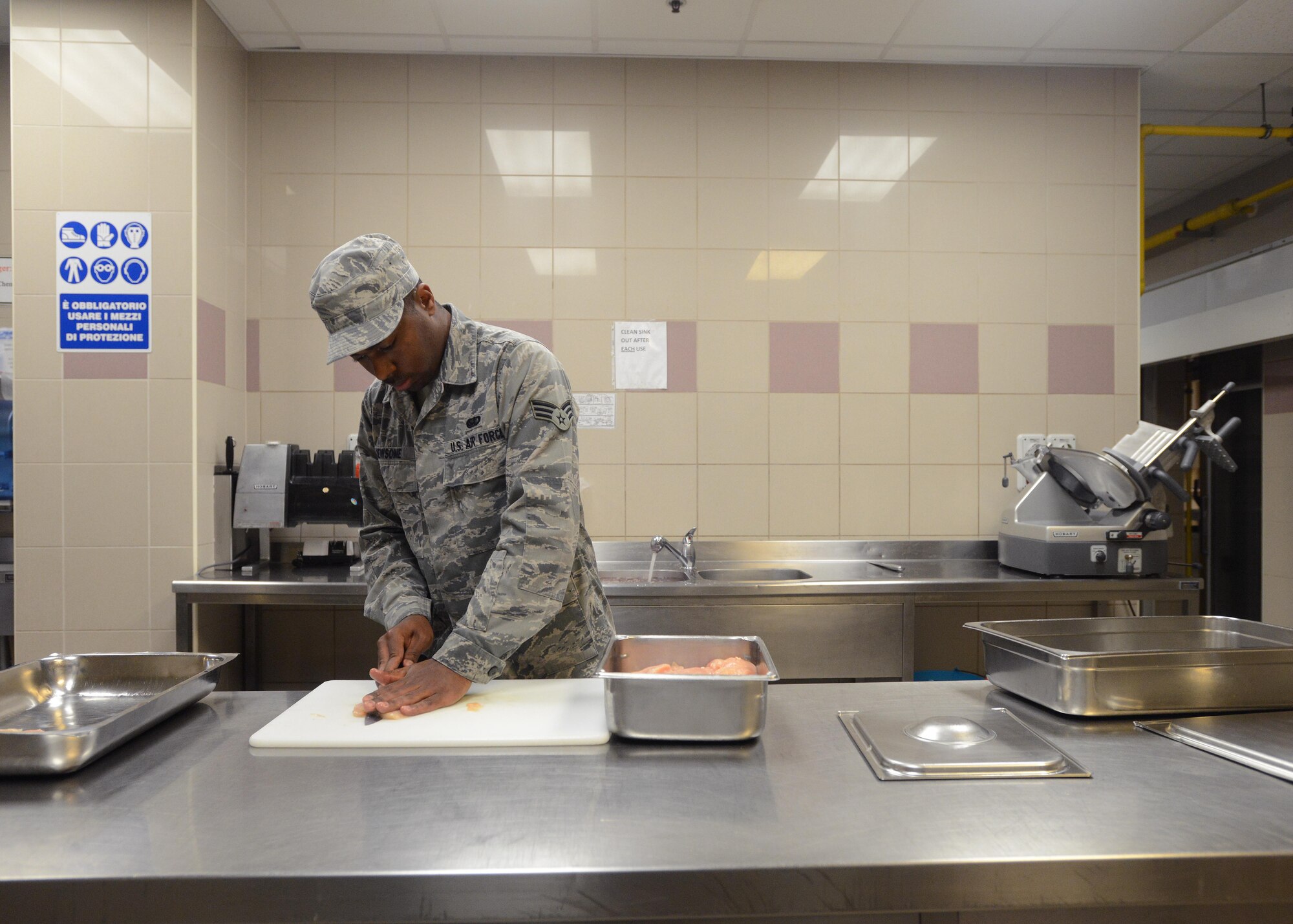 Senior Airman Christopher Newsome, 31st Force Support Squadron food services journeyman, cuts chicken, Sept. 8, 2014, at Aviano Air Base, Italy. Cutting and serving the correct portion sizes help dining facilities remain within their budgets. (U.S. Air Force photo/Airman 1st Class Deana Heitzman)