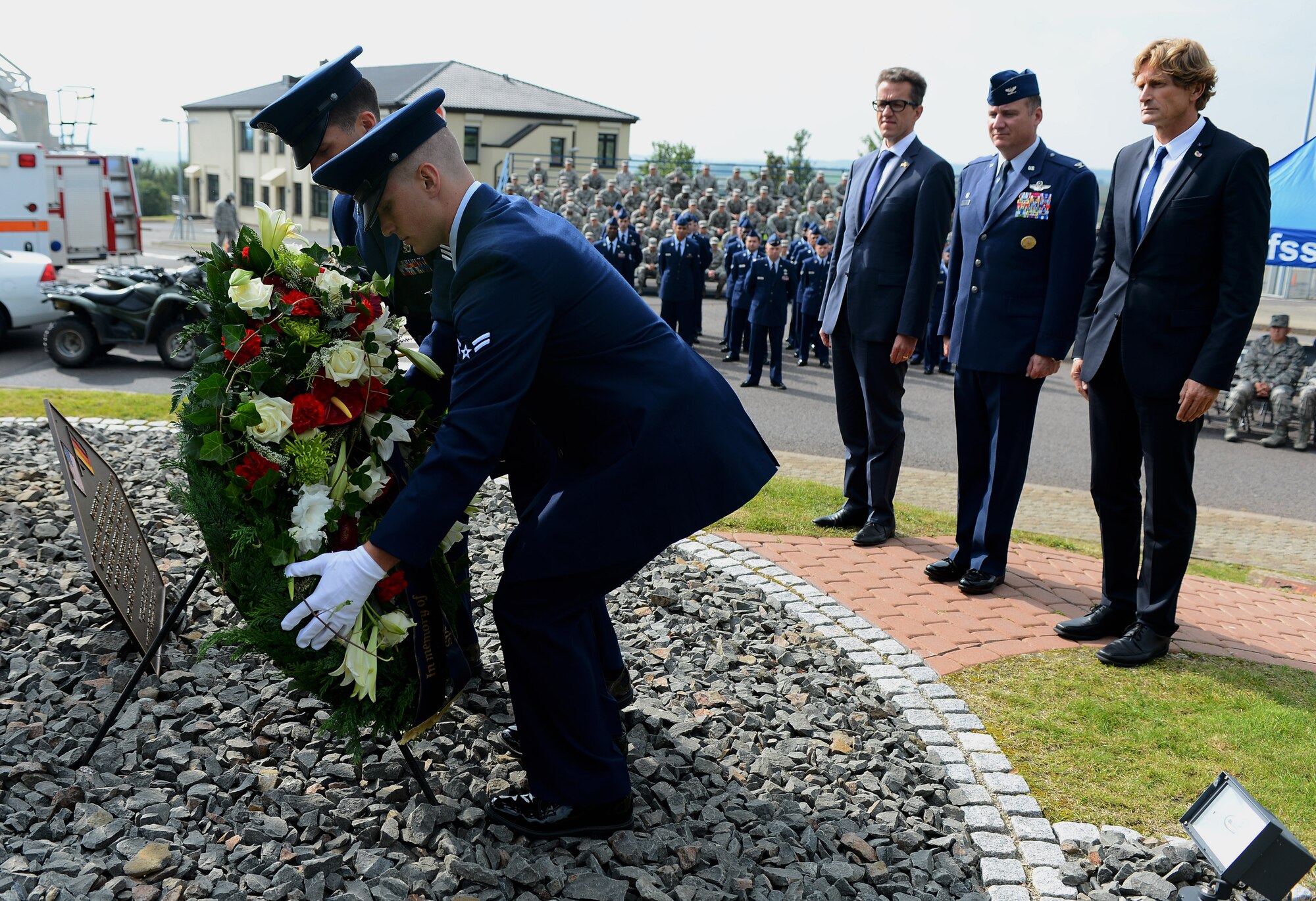 Firefighters from the 52nd Civil Enigneer Squadron lay a wreath during a 9/11 ceremony at the Spangdahlem Air Park Memorial Sept. 11, 2014, at Spangdahlem Air Base, Germany. From left to right, Dr. Joachim Streit,county commissioner of Bitburg-Pruem; U.S. Air Force Col. Pete Bilodeau, 52nd Fighter Wing commander; and Jan Niewodniczanski, president of the Host Nation Council Spangdahlem e.V., were among the guest speakers at the ceremony. The Host Nation Council Spangdahlem e.V. donated the wreath in honor of the ceremony. (U.S. Air Force Photo by Airman 1st Class Luke J. Kitterman/Released)