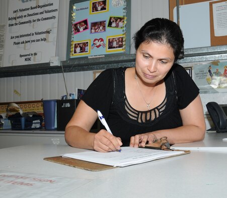 Mara Miller, a volunteer from Honduras and wife of Scott Miller, Joint Special Operations Air Component–Europe, Deputy J3 from Las Vegas, fills in the date on a sign in sheet Sept. 10, 2014, in the community closet on RAF Mildenhall, England. Anyone with a valid ID card, including military members, retirees, spouses and department of defense personnel, can use the community closet. (U.S. Air Force photo/Gina Randall/Released)