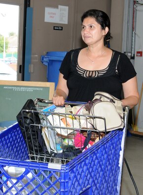 Mara Miller, a volunteer from Honduras and wife of Scott Miller, Joint Special Operations Air Component–Europe, Deputy J3 from Las Vegas, moves donations to be displayed on shelves Sept. 10, 2014, in the community closet on RAF Mildenhall, England. Miller volunteers on Wednesdays and has been a volunteer for five years. (U.S. Air Force photo/Gina Randall/Released)