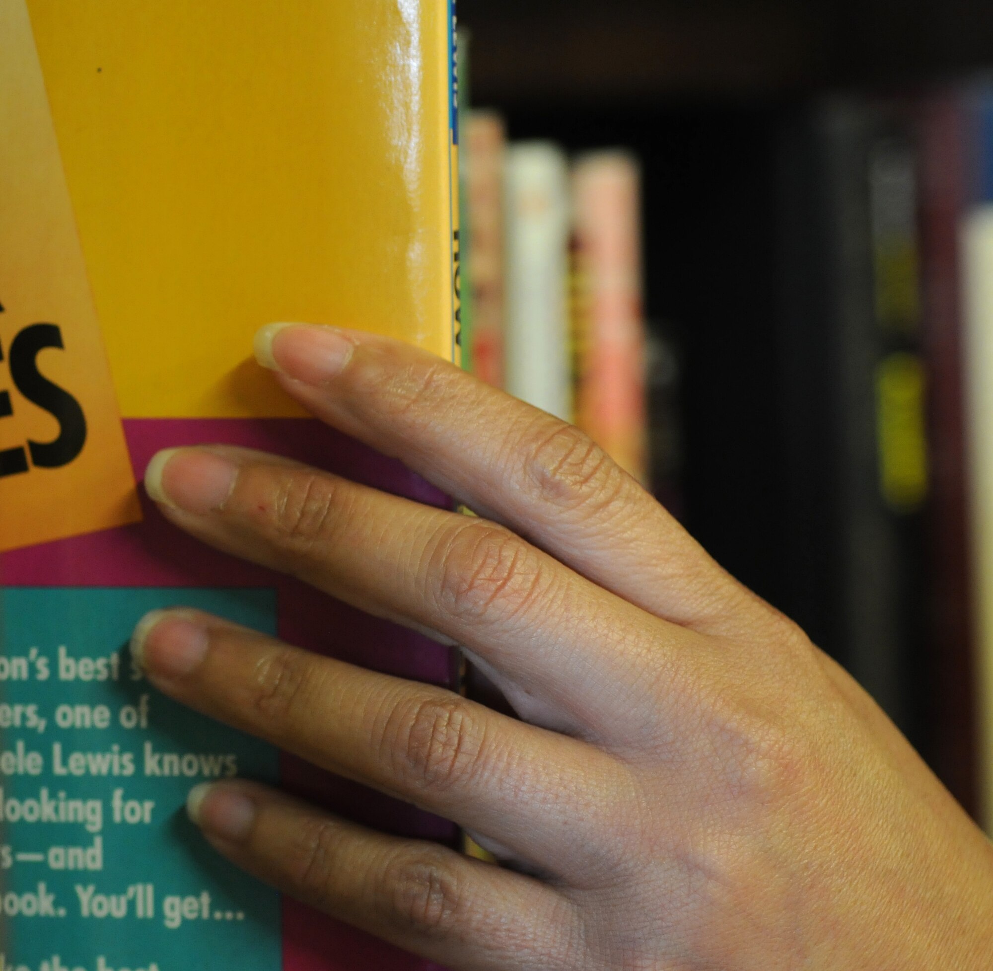 Mara Miller, a volunteer from Honduras and wife of Scott Miller, Joint Special Operations Air Component–Europe, Deputy J3 from Las Vegas, arranges donated books on shelves Sept. 10, 2014, in the community closet on RAF Mildenhall, England. Customers are able to take one large item and two shopping bags for free per visit. (U.S. Air Force photo/Gina Randall/Released)