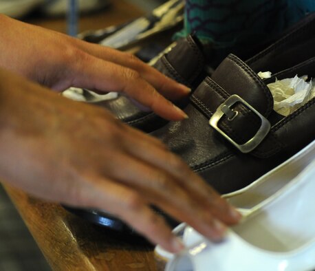 Mara Miller, a volunteer from Honduras and wife of Scott Miller, Joint Special Operations Air Component–Europe, Deputy J3 from Las Vegas, arranges donated shoes on a shelf Sept. 10, 2014, in the community closet on RAF Mildenhall, England. The community closet accepts all donations except large televisions, dirty mattresses or child car seats. (U.S. Air Force photo/Gina Randall/Released)