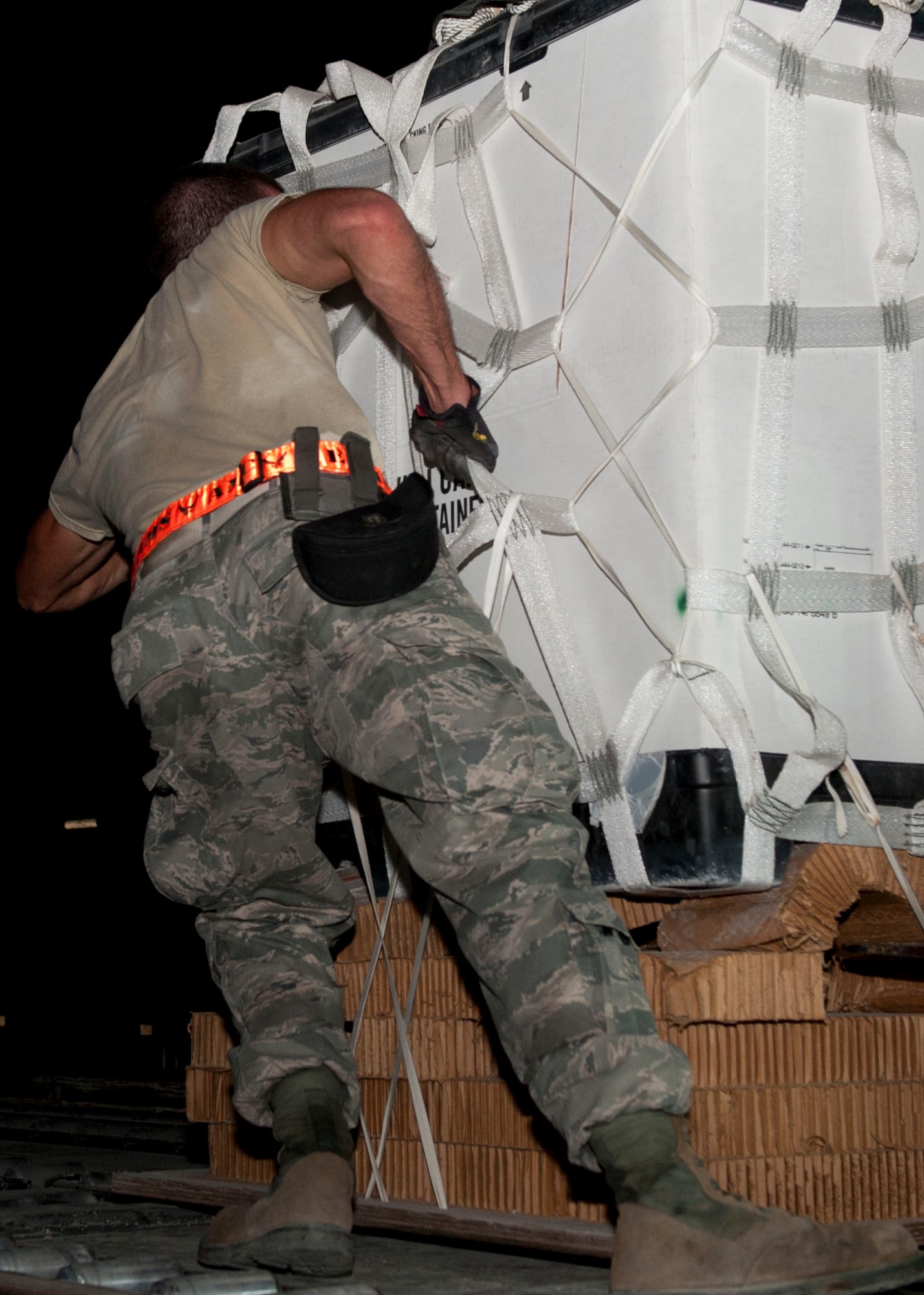 A Service member from the 8th Expeditionary Air Mobility Squadron pulls a completed pallet to be shipped, of food and water for a humanitarian aid drop at Al Udeid Air Base, Qatar, August 30, 2014. The 8th EAMS is the only unit in the U.S. Air Force Central Command Area of Responsibility that provides the specific services they offer. (U.S. Air Force photo by Senior Airman Colin Cates)  