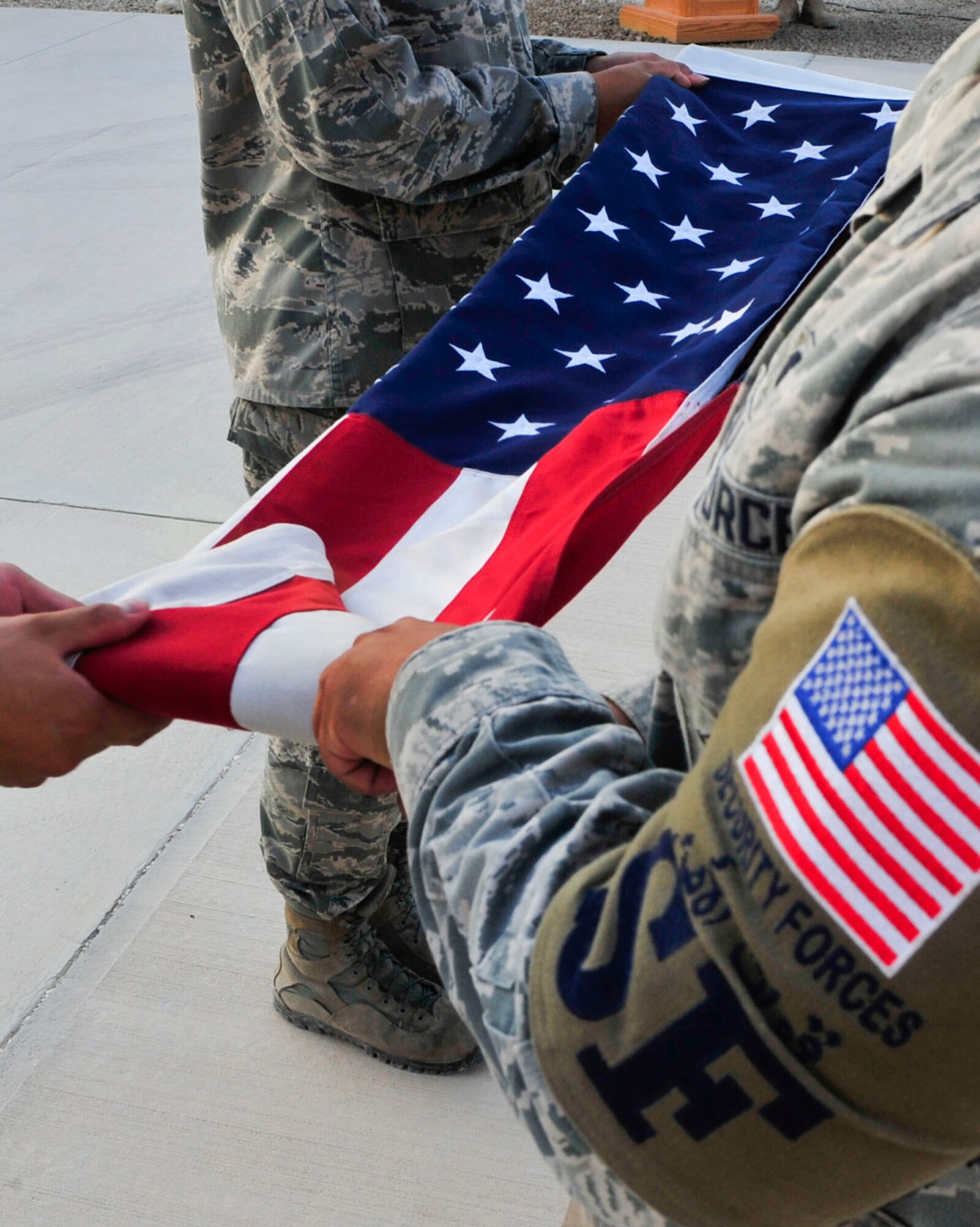 U.S. Air Force Airmen fold an American flag during a retreat ceremony recognizing the thirteenth anniversary of Sept. 11, 2001, at Al Udeid Air Base, Qatar, Sept. 11, 2014.The retreat ceremony signals the end of the official duty day and serves as a ceremony for paying respect to the flag. In this ceremony, respect was paid to the flag and the memory of those lost on Sept. 11, 2001. (U.S. Air Force photo by Senior Airman Colin Cates)  