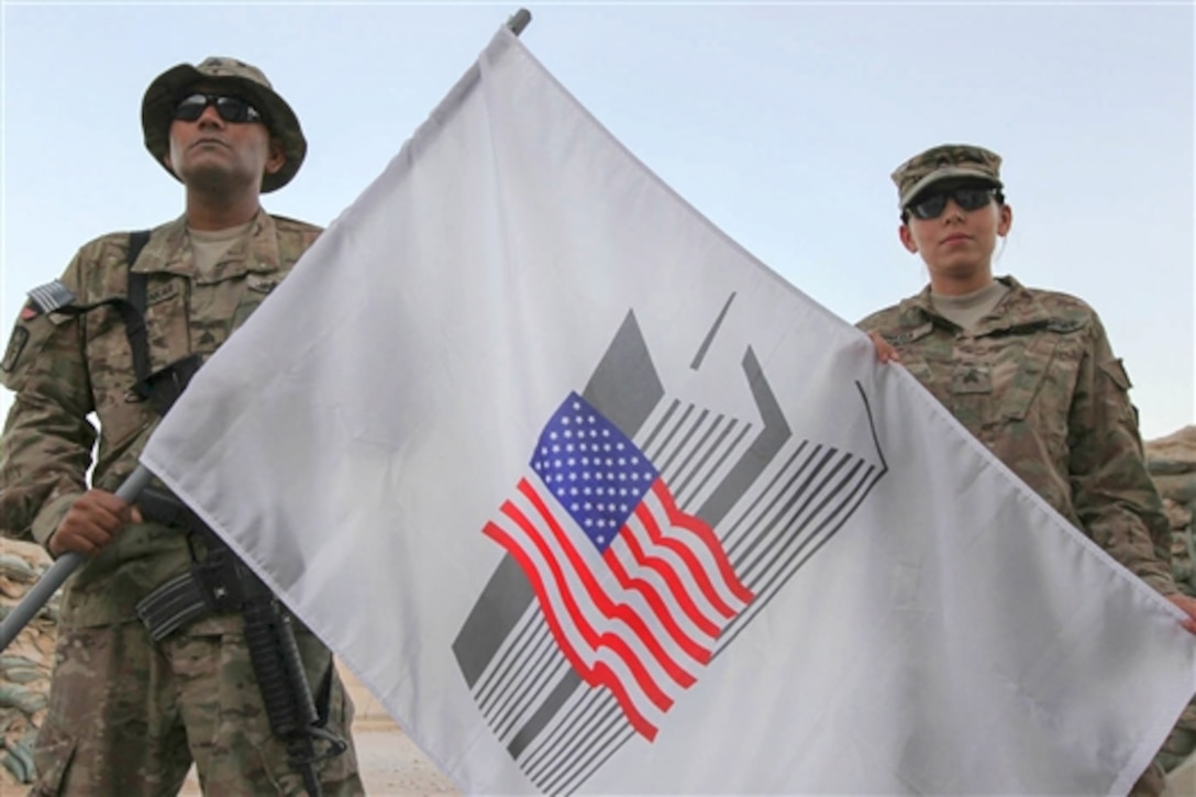 U.S. Army Sgts. Rovin Seosankar, left, and Jennifer Pineda hold a 9/11 commemorative flag on Kandahar Airfield, Afghanistan, Sept. 9, 2014. Seosankar is a financial analyst and Pineda is a finance noncommissioned officer assigned to New York Army National Guard's 4th Financial Management Sustainment Detachment. 