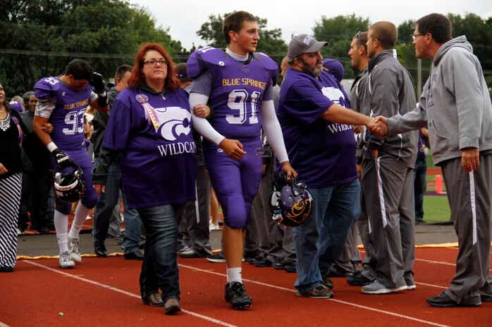 Jaycee D. Pummill, the Blue Springs High School senior long snapper and a 2015 Semper Fidelis All-American Bowl selectee, walks with his parents, Dan and Cindy Pummill, during the Wildcats' senior night before their game against the St. Joseph Central High School Indians at Peve Stadium Sept. 12, 2014. Pummill was ranked 11th overall in snapping by Kohl’s Professional Camps for the 2015 class. He is one of approximately 100 players selected from across the nation to participate in the Semper Fi Bowl next year at the StubHub Center in Carson, Calif.,  on Jan. 4, 2015, and will be aired live on Fox Sports 1 at 6 p.m. Pacific Standard Time.