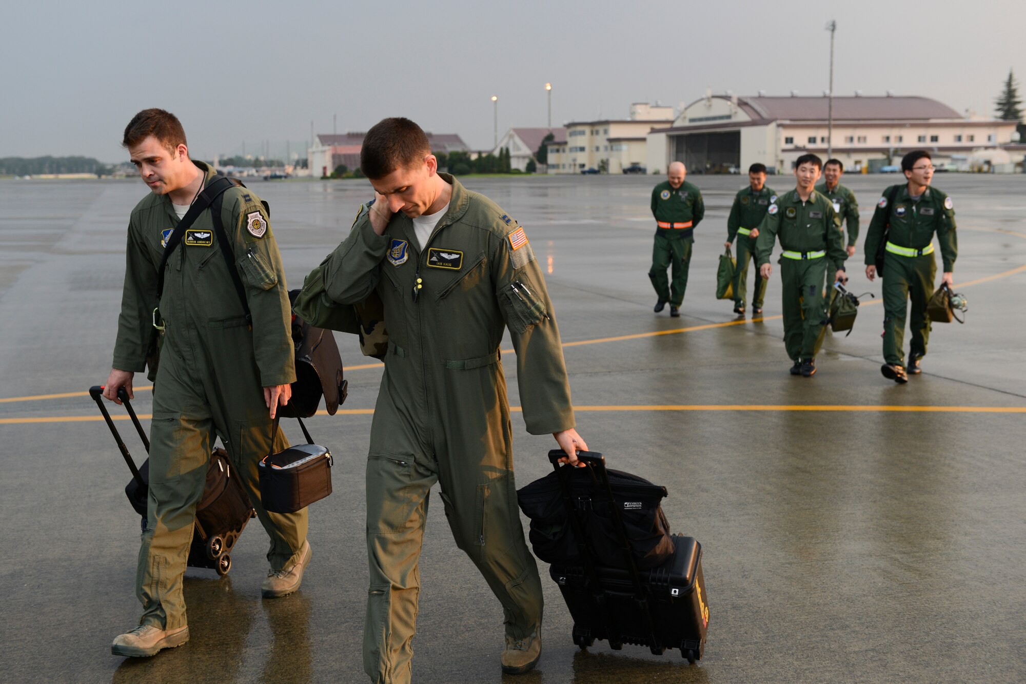 Capts. Nubbin Andrews and Ian Haig, 36th Airlift Squadron aircrew, walk toward a C-130 Hercules with Japan Air Self-Defense Force members at Yokota Air Base, Japan, Sept. 11, 2014. Aircrew with the 36 AS flew with JASDF to showcase their night vision goggle capabilities and display the benefits NVG provide during dark missions. (U.S. Air Force photo by Staff Sgt. Cody H. Ramirez/Released)