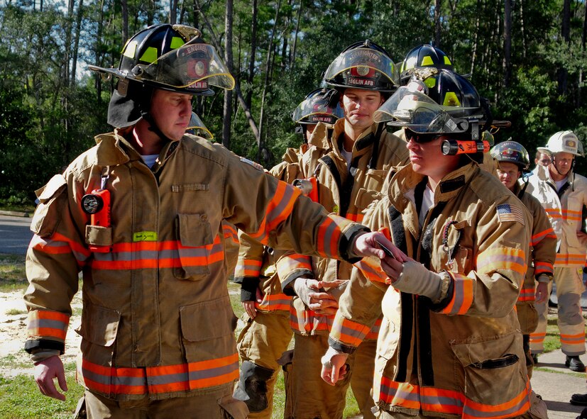 An Eglin Air Force Base firefighter hands off identification tags to another firefighter during the annual 9/11 memorial tower climb, Sept. 11.  Firefighters carried the tags of each of the 343 firefighters killed on 9/11 to the top of the air traffic control tower to be placed on a memorial display.  Once at the top the name was read aloud.  The event ended with participants hanging the display over the balcony of the tower with an American Flag. (Courtesy photo)