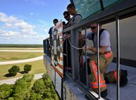 Eglin Air Force Base firefighters attach the 9/11 memorial display to the balcony of the air traffic control tower Sept. 11. Firefighters carried identification tags of each of the 343 firefighters killed on 9/11 to the top of the control tower to be placed on the display.  Once at the top, the name was read aloud.  The event ended with participants hanging the display over the balcony of the tower with an American Flag. (U.S. Air Force photo/Tech. Sgt. Cheryl L. Foster)