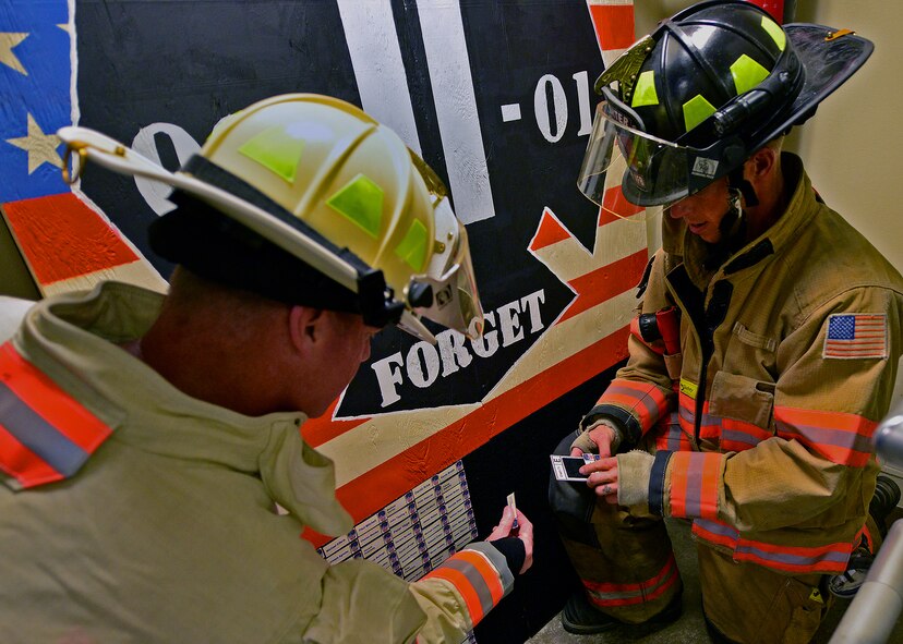 An Eglin Air Force Base firefighter presents a tag with a name of one of the 343 firefighters killed Sept. 11, 2001 to Fire Chief Mark Giuliano after ascending to the top 11-story air traffic control tower Sept. 11. When each name was delivered to the top of the tower it was read aloud. The event ended on top of the tower with participants hanging the tag display over the balcony with an American Flag. (U.S. Air Force photo/Tech. Sgt. Cheryl L. Foster)