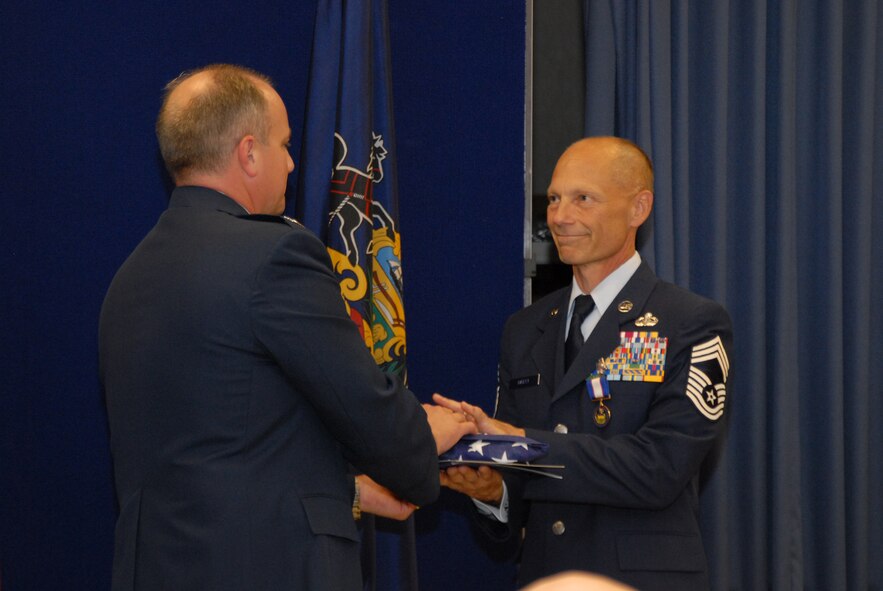 In honor of his retirement, Chief Master Sgt. Cameron Bailey, 193rd Regional Support Group superintendent, accepts an American Flag flown in his honor from Col. Kevin Derickson, 193rd RSG commander. Chief Bailey has served the Pennsylvania Air National Guard for more than 30 years, entering in 1981 as a ground radio communications specialist with the 193rd Electronics Combat Group. Some of his distinguished military positions include commandant of the Lightning Force Academy and advisor to the Air Combat command and Air Force Space Command’s Inspector General offices. (Staff Sgt. Claire Behney/Released)