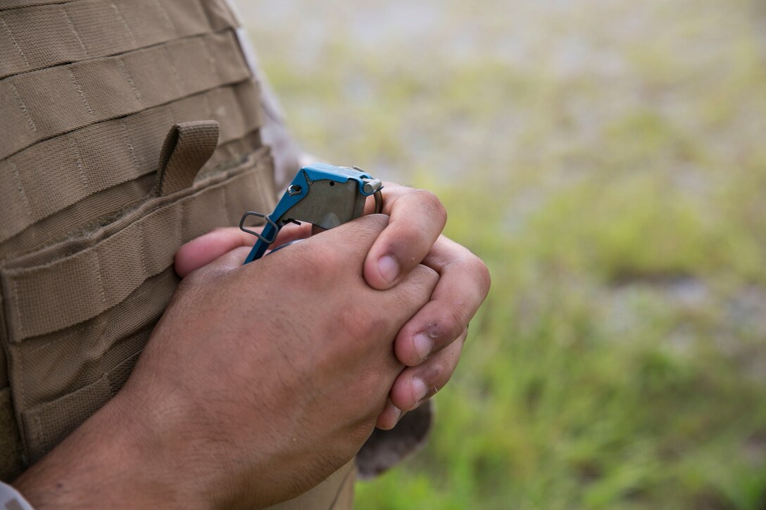 Lance Cpl. Eric Basora, from San Antonio, Texas, holds an M69 training grenade Aug. 29 at Camp Hansen. The Marines held the grenades against their chest as one of many range safety measures. Basora is a military policeman with Company A, 3rd Law Enforcement Battalion, III Marine Expeditionary Force Headquarters Group, III MEF. (U.S. Marine Corps photo by Lance Cpl. Devon Tindle/Released)