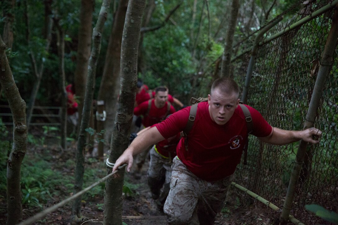 Marines with 3rd Intelligence Battalion, III Marine Expeditionary Force Headquarters Group, climb a staircase in the jungle Sept. 11 during an endurance course on Camp Hansen as part of a 9/11 commemorative training day. After the physical training, 1st Sgt. Maurice Bease and Lt. Col. Mike D. Reilly, two Marines with the battalion who worked at the Pentagon on 9/11, recounted their experiences. “I wanted people to understand, the significance of 9/11 to our generation,” said Bease, the company first sergeant of Production and Analysis Company, 3rd Intel Bn., III MHG, III MEF. “With each generation come significant events that shape the entire generation. 9/11 was that event.” Bease is from Baltimore, Maryland. Reilly is from Houston, Texas, and the commanding officer of 3rd Intel Bn.