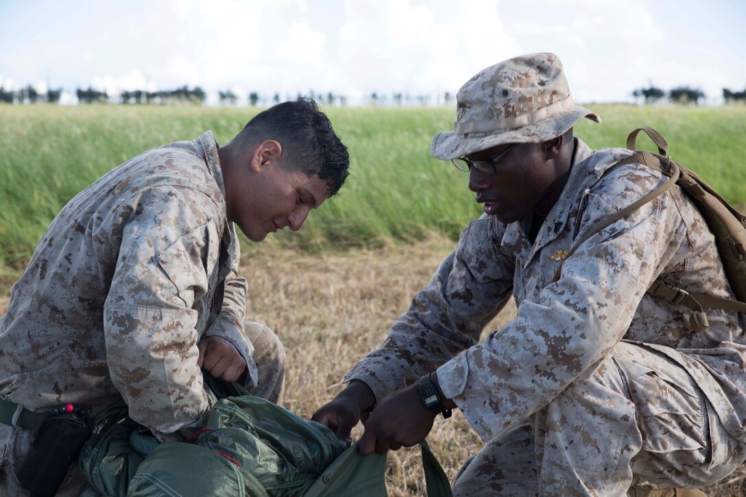 Cpls. David Meneses, left, and Devon J. Henderson pack an MC-7 parachute system following its use in a low-level static-jump Aug. 26 at Ie Shima Airfield, Okinawa, Japan. For the training jumps, the Marines were weighed down with approximately 150 pounds of equipment, which has the potential to affect the flight path of their descent after the parachute canopy opens. Meneses is from Orlando, Florida, and Henderson is from Fayetteville, North Carolina. Both are airborne and air delivery specialists with Combat Logistics Regiment 3, 3rd Marine Logistics Group, III Marine Expeditionary Force. (U.S. Marine Corps photo by Lance Cpl. Matt Myers/Released)
