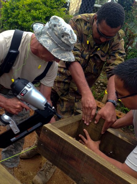 Chief Master Sgt. Robert Davis, 154th Civil Engineer Squadron chief enlisted manager and structures subject matter expert, goes over construction plans with members of the Hawaii Air National Guard 154th Civil Engineer Squadron who have been working on the construction of two new dormitories at Togoba Secondary School in Mount Hagen, Papua New Guinea, as part of Pacific Unity 14-8. PACUNITY helps cultivate common bonds and fosters goodwill between the U.S. and regional nations through multi-lateral humanitarian assistance and civil military operations.  (U.S. Air Force photo by Airman 1st Class Jaimie Aquino/Released)                               