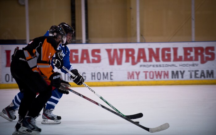 Tech. Sgt. Christopher Judge (blue jersey), captain of the Nellis Air Force Base hockey team, jostles for the puck with a member of the Desert Foxes hockey team in Las Vegas Sept. 10, 2014. Judge made key defensive stops and provided an offensive spark in the team’s season-opening 7-6 victory over the Desert Foxes. Judge is the cyber operations NCO in charge of the 328th Weapons Squadron. (U.S. Air Force photo by Staff Sgt. Siuta B. Ika)