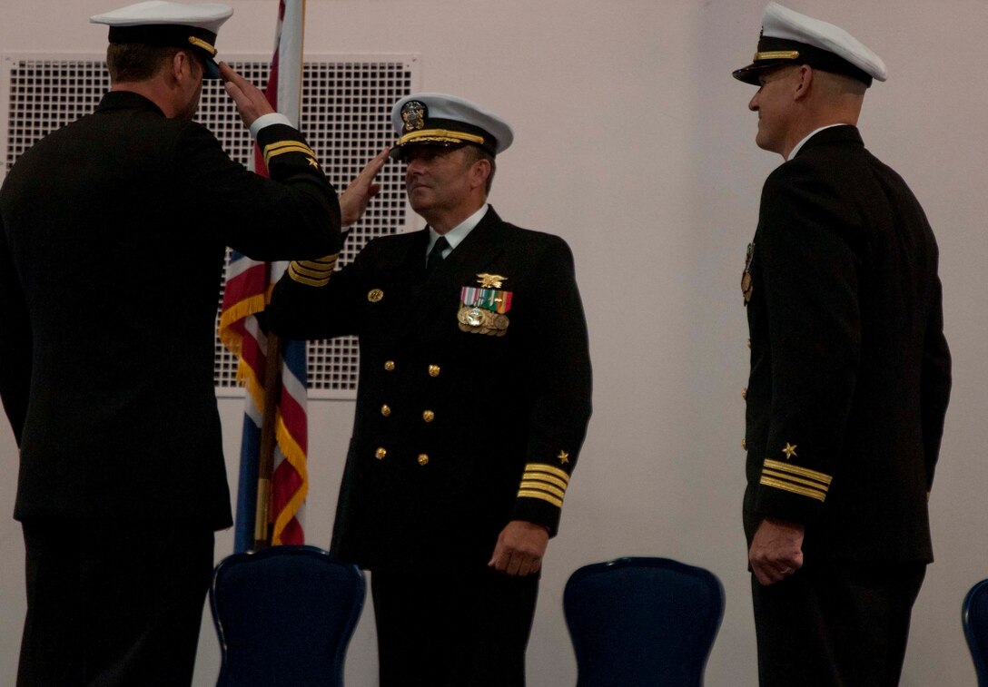 Navy Lt. Ryan Clapper salutes Navy Capt. Scott McMahon during the Navy Operational Support Center’s change-of-command ceremony Sept. 13 in the Fall Hall Community Center. Clapper received command of the NOSC from Navy Lt. Cmdr. Chad Tidwell, right. (U.S. Air Force photo by Airman Malcolm Mayfield)