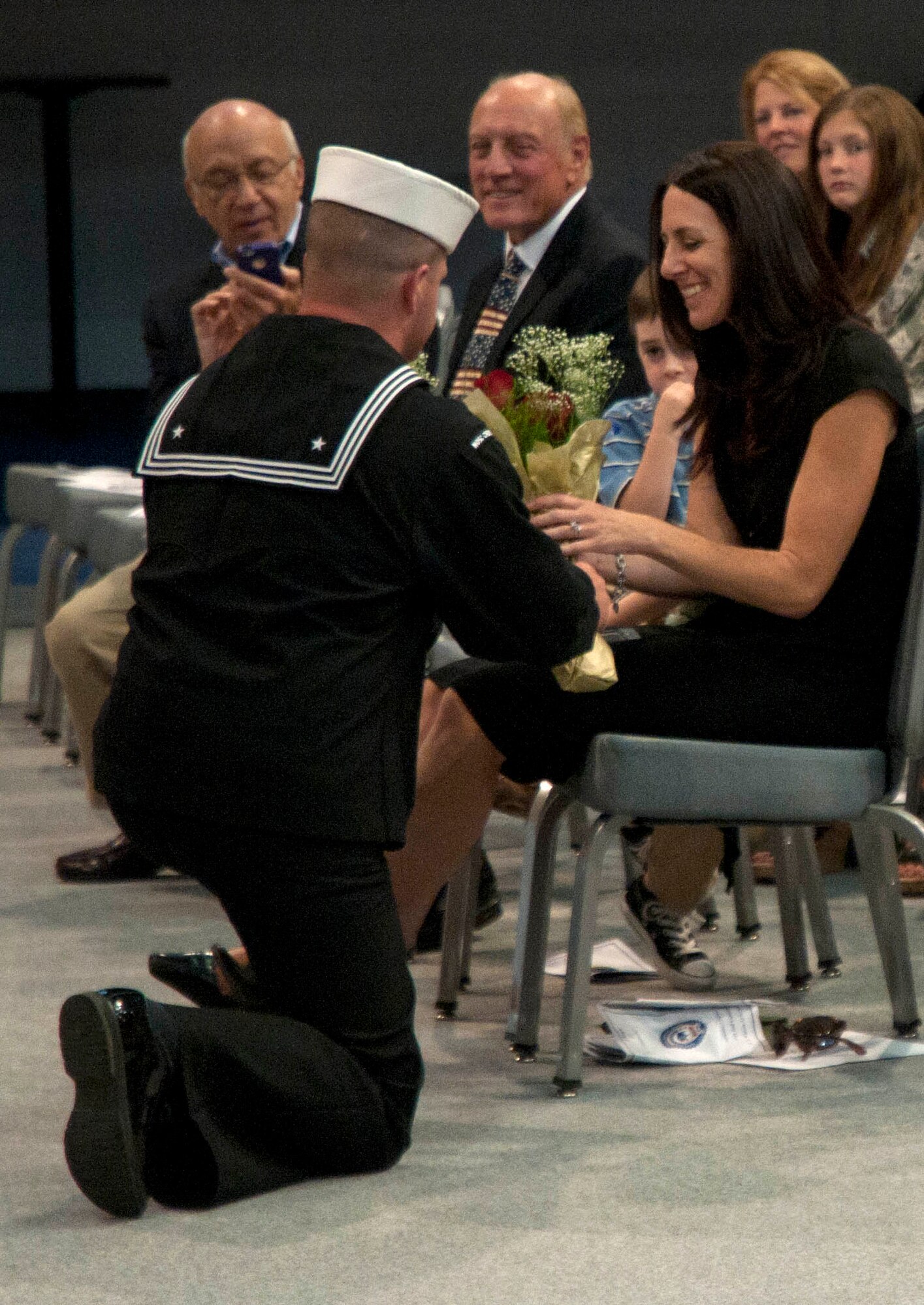 A sailor presents flowers to Navy Lt. Ryan Clapper's wife after Clapper took command of the Naval Operational Support Center during a change-of-command ceremony Sept. 13 in the Fall Hall Community Center. (U.S. Air Force photo by Airman Malcolm Mayfield)