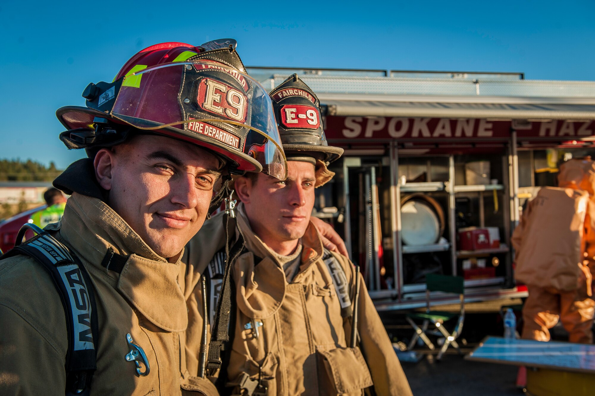 Staff Sgt. Daryl Teague and Senior Airman Chandler Tuscany, both 92nd Civil Engineer Squadron firefighters, take a moment before donning their self-contained breathing apparatuses while performing decontamination support with other regional firefighters near the spill zone of a hazardous materials incident near the Washington-Idaho state line Sept. 14, 2014. Four Fairchild Air Force Base firefighters, one technician and a variety of support staff as well as the base’s mobile decontamination and rehabilitation unit joined two dozen other firefighters, trucks and equipment from Spokane regional fire districts in response to the incident. (U.S. Air Force photo by Staff Sgt. Benjamin W. Stratton/Released)