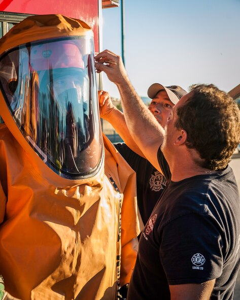 Craig Sayler, a 92nd Civil Engineer Squadron firefighter, gets his hazardous material suit checked over before joining other regional firefighters in the spill zone of a hazardous materials incident near the Washington-Idaho state line Sept. 14, 2014. A tanker truck leaking anhydrous trimethylamine, a flammable substance used in making solvents, animal feed supplements and products consumed by the paper, oil and gas industries, prompted emergency responders to shut down Interstate 90 garnering immense regional response including Fairchild Air Force Base firefighters. (U.S. Air Force photo/Staff Sgt. Benjamin W. Stratton)