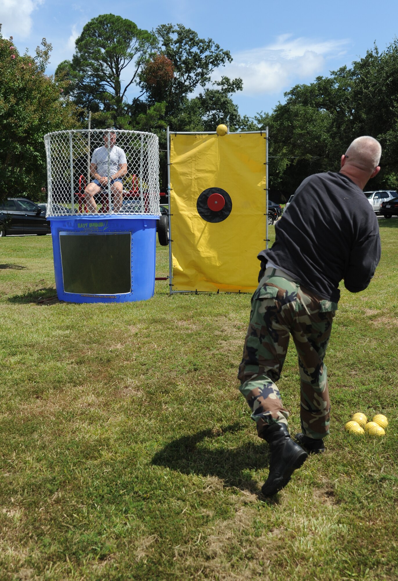 Chief Master Sgt. Derick Stepp, 81st Security Forces Squadron, throws a ball toward the dunking booth target with Brig. Gen. Patrick Higby, 81st Training Wing commander, waits to be dunked during the Fisher House Fundraiser paintball tournament Sept. 12, 2014, at the paintball complex, Keesler Air Force Base, Miss.  The event also included food and games. (U.S. Air Force photo by Kemberly Groue)