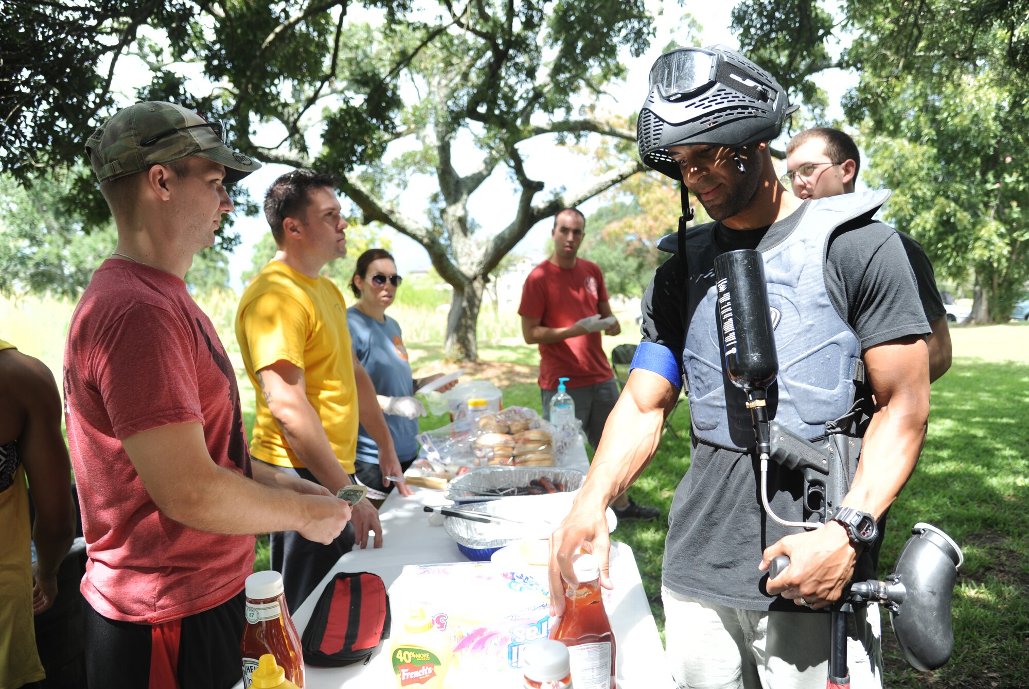 Staff Sgt. Dustin Hawthorne, 335th Training Squadron, receives payment from Staff Sgt. Errol Wallace, 81st Logistics Readiness Squadron, as he prepares a hotdog before competing in the Fisher House Fundraiser paintball tournament Sept. 12, 2014, at the paintball complex, Keesler Air Force Base, Miss.  The event also included games and a dunking booth.  (U.S. Air Force photo by Kemberly Groue)
