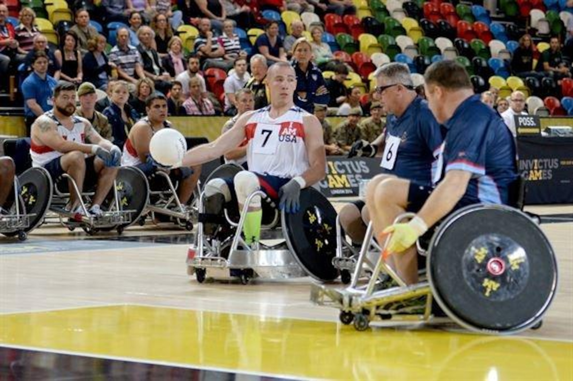 Army Sgt. Ryan McIntosh, representing the U.S., passes the ball around two defenders during a wheelchair rugby match against Australia Sept. 12, 2014, at the 2014 Invictus Games in London. The U.S. won the match 14-4. Invictus Games is an international competition that brings together wounded, injured and ill service members in the spirit of friendly athletic competition. American Soldiers, Sailors, Airmen and Marines are representing the U.S. in the competition which is taking place Sept. 10-14. (U.S. Navy photo/Mass Communication Specialist 2nd Class Joshua D. Sheppard)
