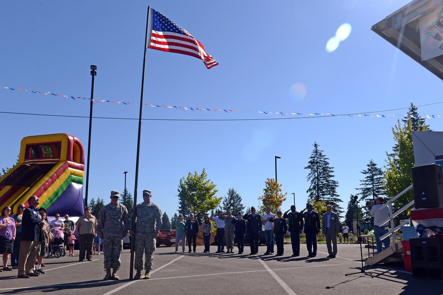 Joint Base Lewis-McChord service members and their families pay respect to the U.S. flag during the national anthem Sept. 13, 2014, during the Rotary Club of Hawks Prairie 12th Military Appreciation Day at Lacey, Wash. The event was open to all service members and their families and included free food and entertainment. (U.S. Air Force photo/Airman 1st Class Jacob Jimenez) 