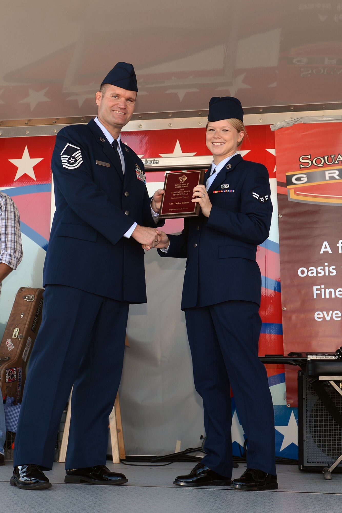 Master Sgt. James Nance, 627th Communications Squadron knowledge management center section chief, presents Airman 1st Class Taylor Walker, 627th Air Base Group executive assistant, with the Distinguished Patriot Award Sept. 13, 2014, during the Rotary Club of Hawks Prairie 12th Military Appreciation Day at Lacey, Wash. Walker manages the 627th ABG’s decorations, evaluations and awards program and is the functional area records manager for more than 55 offices. (U.S. Air Force photo/ Airman 1st Class Jacob Jimenez)