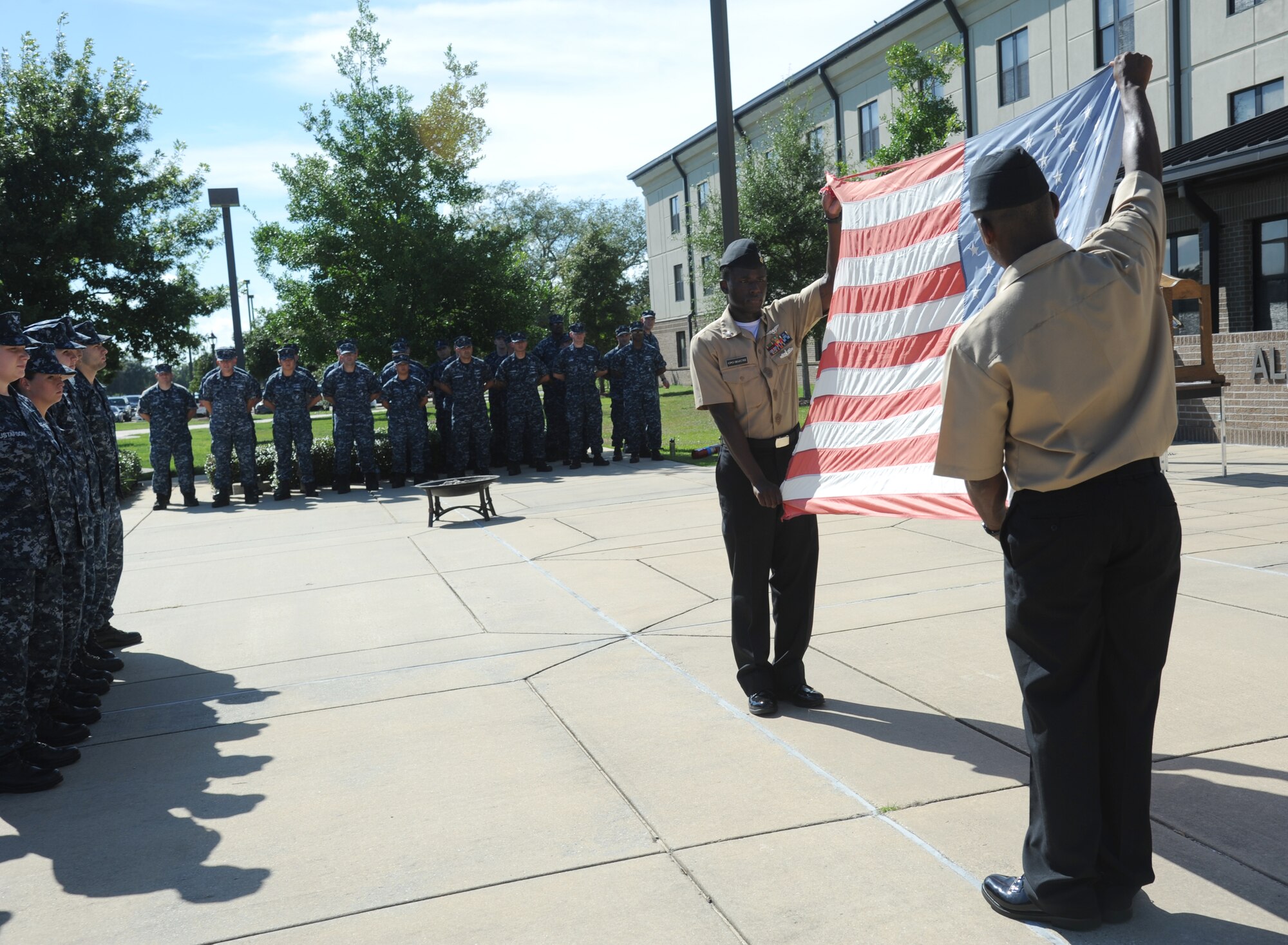 Petty Officers 1st Class Quintron Perry and Sedric Jones, Center for Naval Aviation Technical Training Unit Keesler, display a worn U.S. flag to be retired during a remembrance ceremony Sept. 11, 2014, Keesler Air Force Base, Miss.  The ceremony also honored those who lost their lives during the 9/11 attacks. (U.S. Air Force photo by Kemberly Groue)