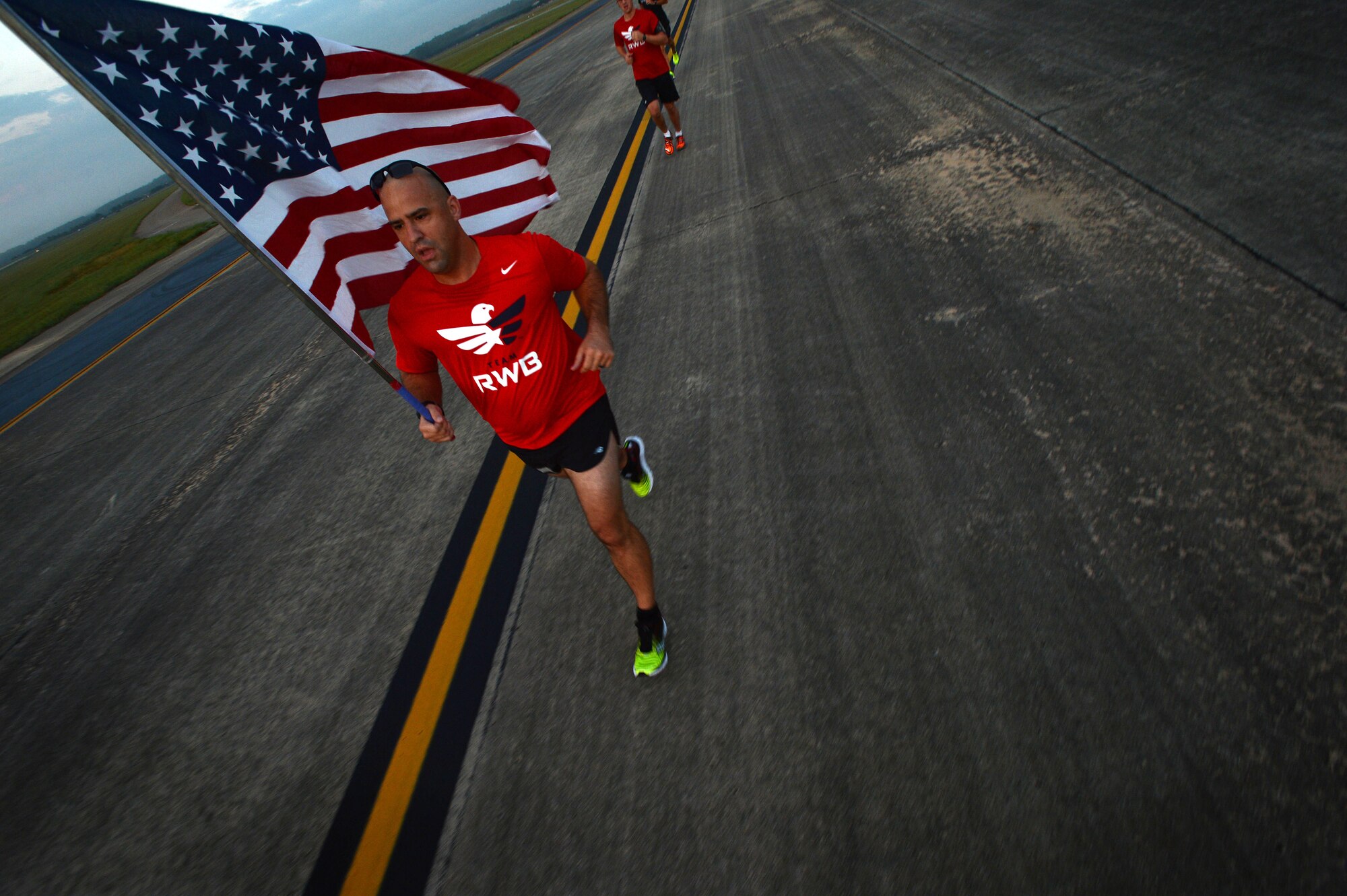 U.S. Army Sgt. 1st Class Shaun Benoit, U.S. Army Central international military affairs Central and South East Asia branch NCO in charge, runs with an American flag during a flightline 5k at Shaw Air Force Base, S.C., Sept. 11, 2014. During the 9/11 memorial run, approximately 60 Team Shaw members completed the 3.1 mile race. (U.S. Air Force photo by Airman 1st Class Jensen Stidham/Released) 