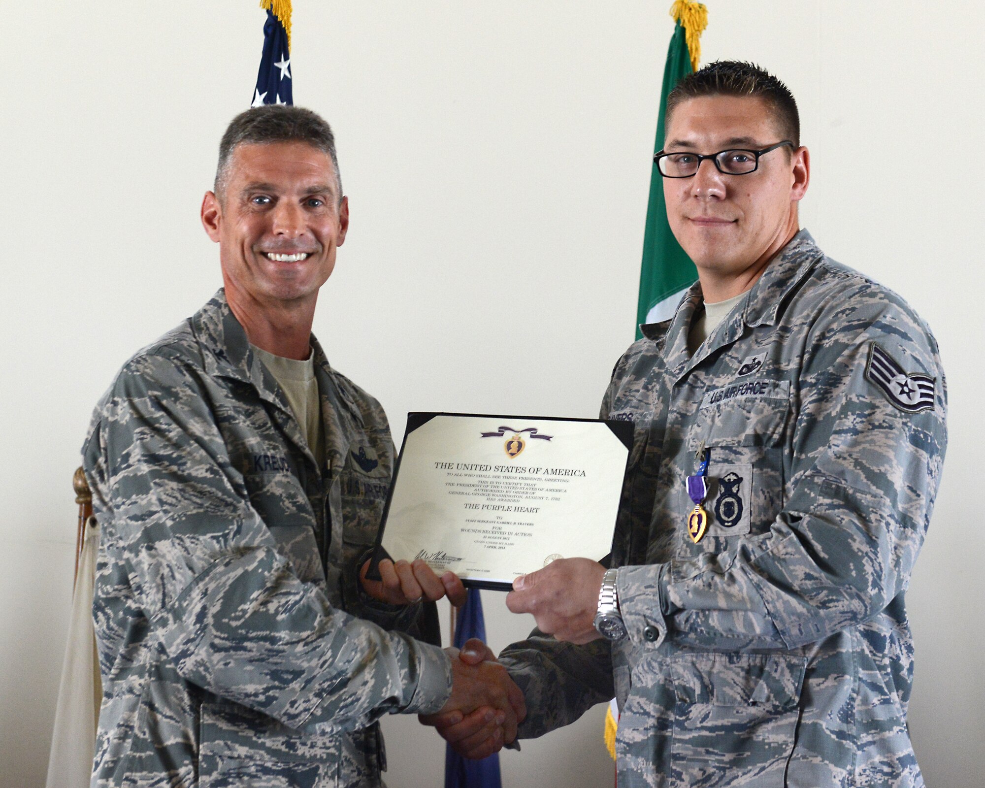 (From left) Col. Gregory Kreuder, 31st Fighter Wing vice commander, presents Staff Sgt. Gabriel Travers, 31st Security Forces Squadron K-9 handler, with the Purple Heart, Aug. 1, 2014, at Aviano Air Base, Italy. During a deployment to Kandahar Airfield, Afghanistan, in 2012, Travers and his K-9 partner, Tora, were tasked to search for improvised explosive devices when he was injured from an IED blast. (U.S. Air Force photo/Airman 1st Class Ryan Conroy)