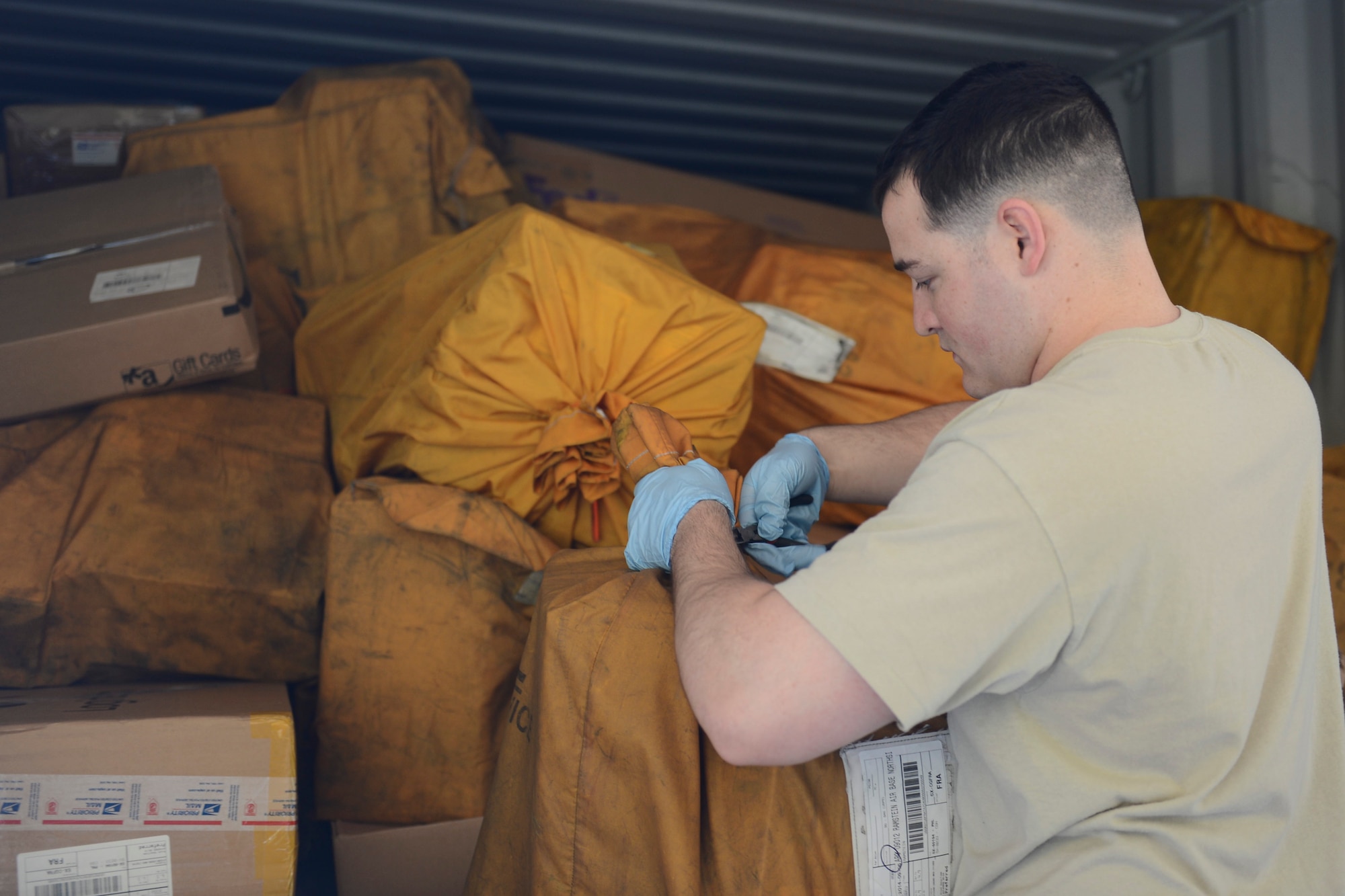 Senior Airman John Brooks, 86th Communications Squadron postal specialist, cuts open bags of mail inside of a postal truck at the Northside post office on Ramstein Air Base, Sept. 9, 2014. In an average month, Ramstein processes about 55,000 personal packages and about 5,000 official packages. (U.S. Air Force photo/Airman 1st Class Michael Stuart)