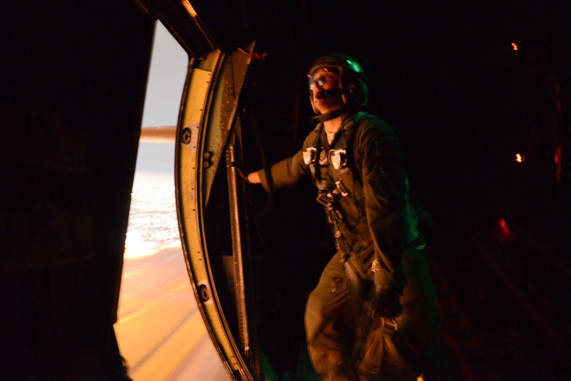 Staff Sgt. Kyle Favorite, 36th Airlift Squadron loadmaster, prepares to throw a training package from a C-130 Hercules over the flightline at Yokota Air Base, Sept. 11, 2014. Favorite was the one of many 36 AS members who was on the flight to showcase their night vision goggle capabilities to Japan Air Self-Defense Force members. The team ‘killed two birds with one stone,’ by also completing routine training during the flight. (U.S. Air Force photo by Staff Sgt. Cody H. Ramirez/Released)