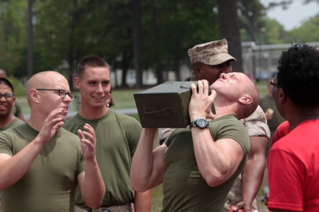 Private First Class Scott Johnson (middle), student, Financial Management School (FMS), Marine Corps Combat Service Support Schools (MCCSSS), performs ammo can lifts for the combat conditioning race during MCCSSS field meet aboard Camp Johnson, N.C., April 25, 2014. Marine students and staff of MCCSSS participate in the field meet to encourage camaraderie and motivation among all the schools The field meet is held semi-annually and consists of 8 events which include tugs of war, stretcher carry, combat conditioning, soccer, volleyball, etc. After the competition concluded the MCCSSS Commanders Cup was awarded to the Marine students and staff of FMS. (U.S. Marine Corps Combat Camera photo by Sergeant Mark E. Morrow/Released)